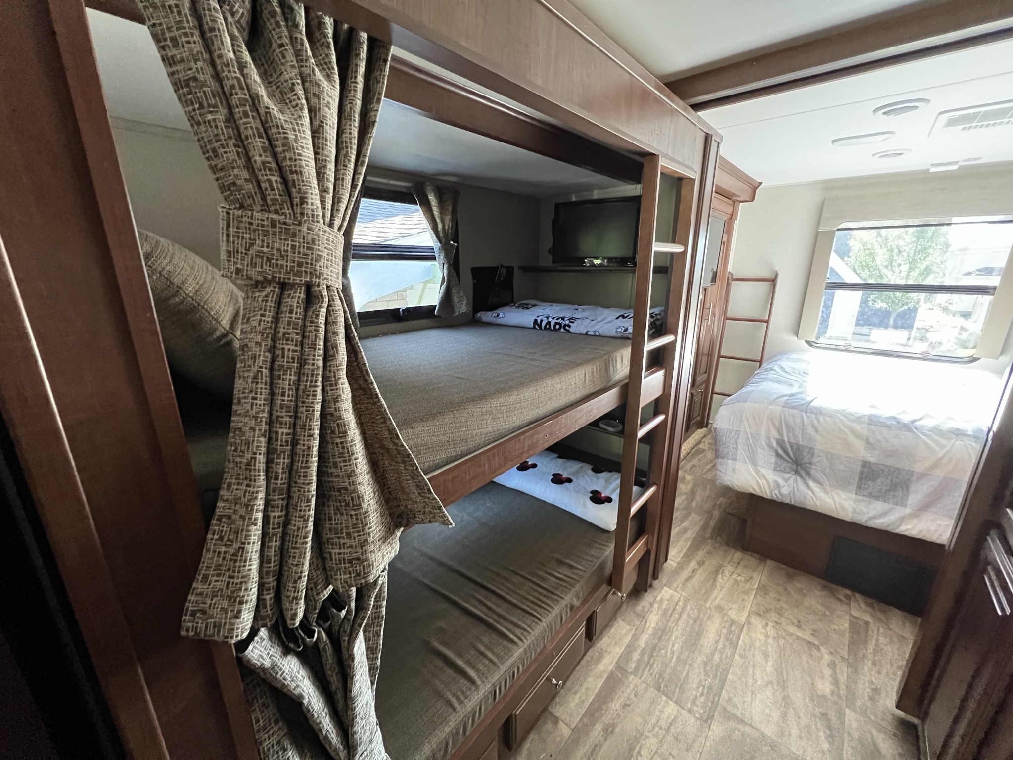Cozy RV rental interior featuring bunk beds with privacy curtains, a master bed, and a TV.. Georgetown 351 DS Bunkhouse 2017