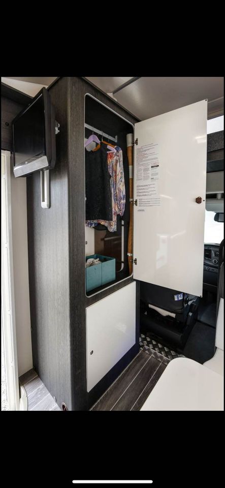 RV rental interior featuring a smart, compact wardrobe with hanging clothes, TV, and storage for efficient mobile living.. Rollerteam Zefiro 675 2021