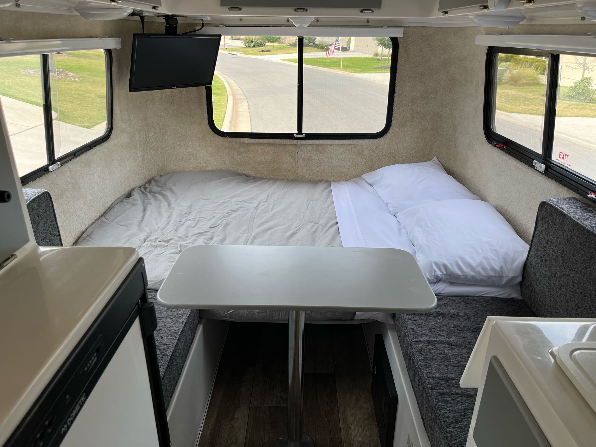 Inside an RV rental: full bed, small table, and panoramic windows offer comfy travel.. Casita Liberty 2021