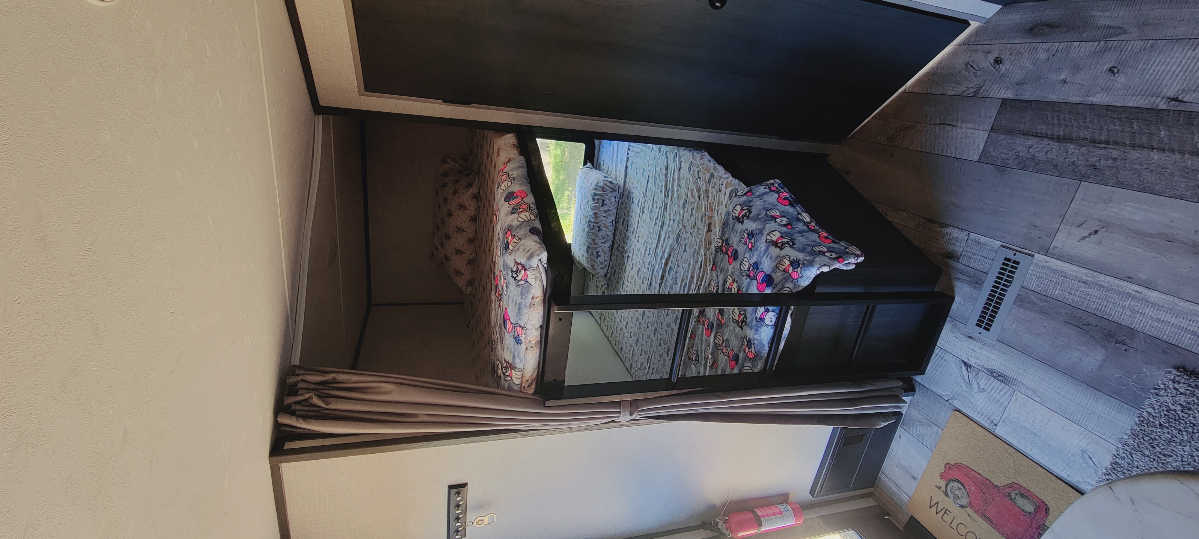 RV rental: two bunk beds, each with distinct patterned blankets, a window view, and wood-look floor.. Aspen Trail Aspen Trail Trailer 2021