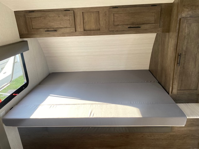 RV rental bedroom with comfortable gray bed, overhead storage, and window.. Forest River 1768BHSK 2022
