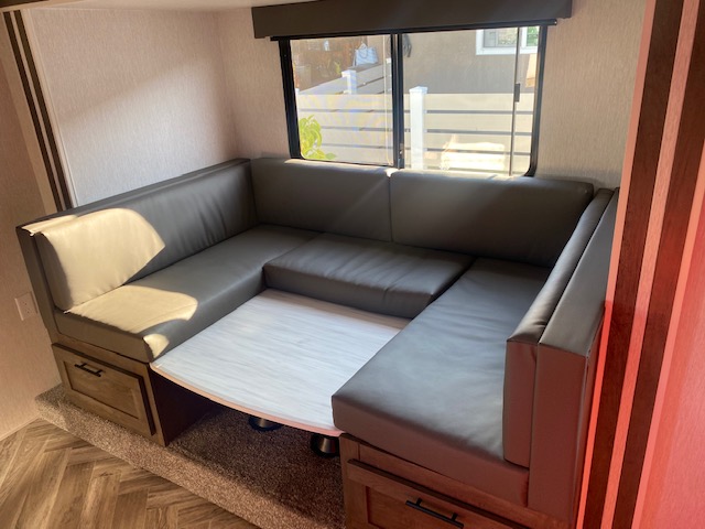 U-shaped dinette with dark cushions & light table in an RV rental. Offers spacious seating & natural light.. Forest River 1768BHSK 2022