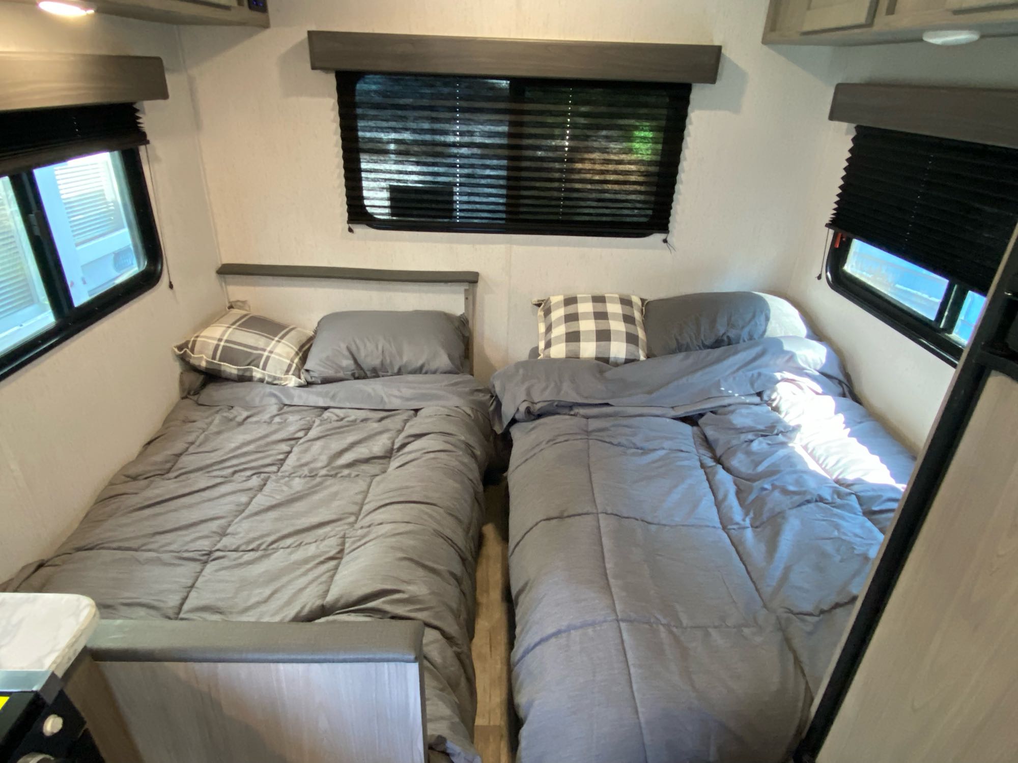 Cozy RV rental interior showing two comfortable single beds with grey bedding. Windows have dark blinds.. Dutchmen Coleman lantern LT 2022