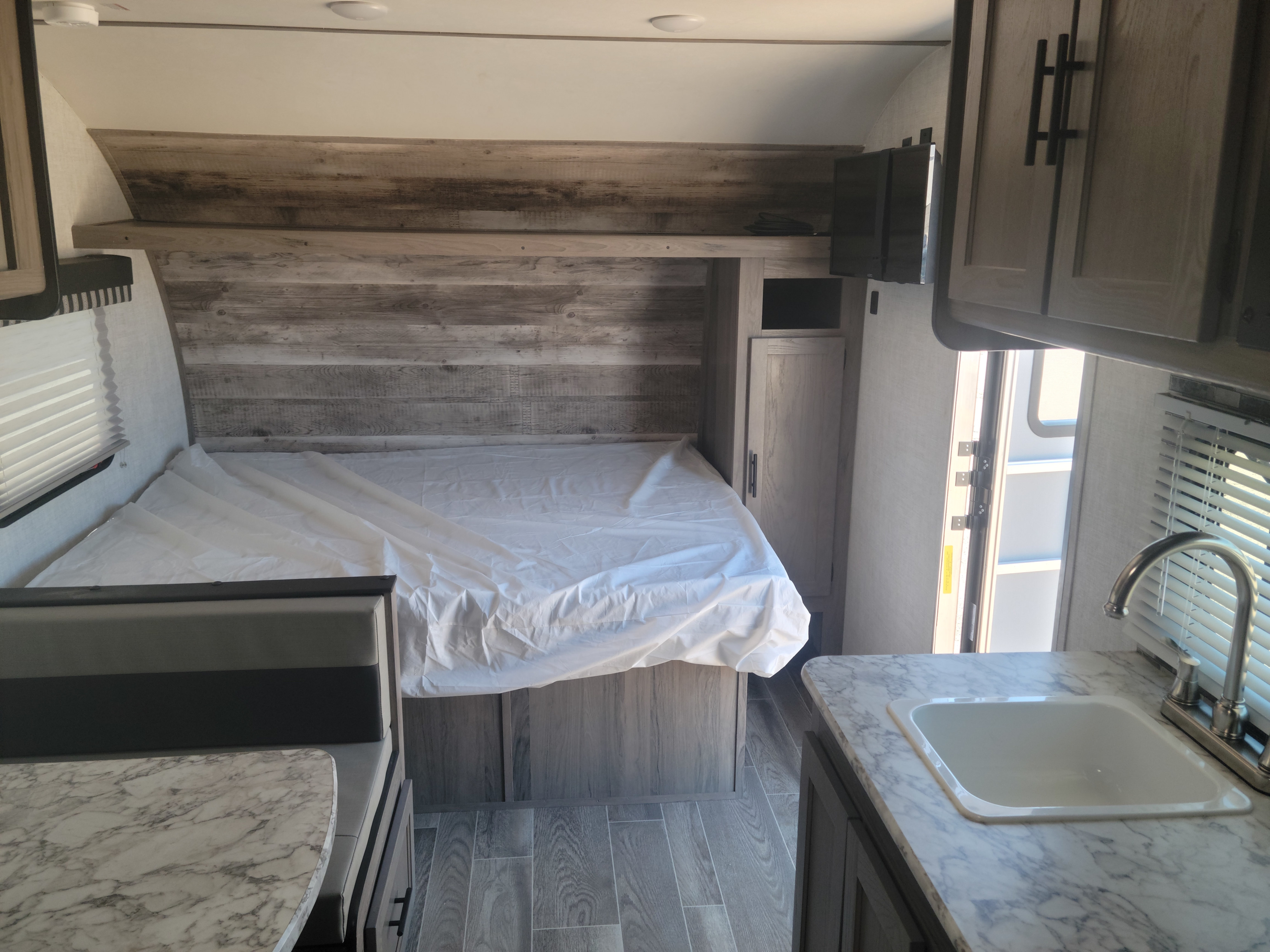 Inside a modern RV rental: view of bed area, dinette with table, and compact kitchen with sink. Perfect for trips!. Gulf Stream Ameri-Lite Super Lite 2021
