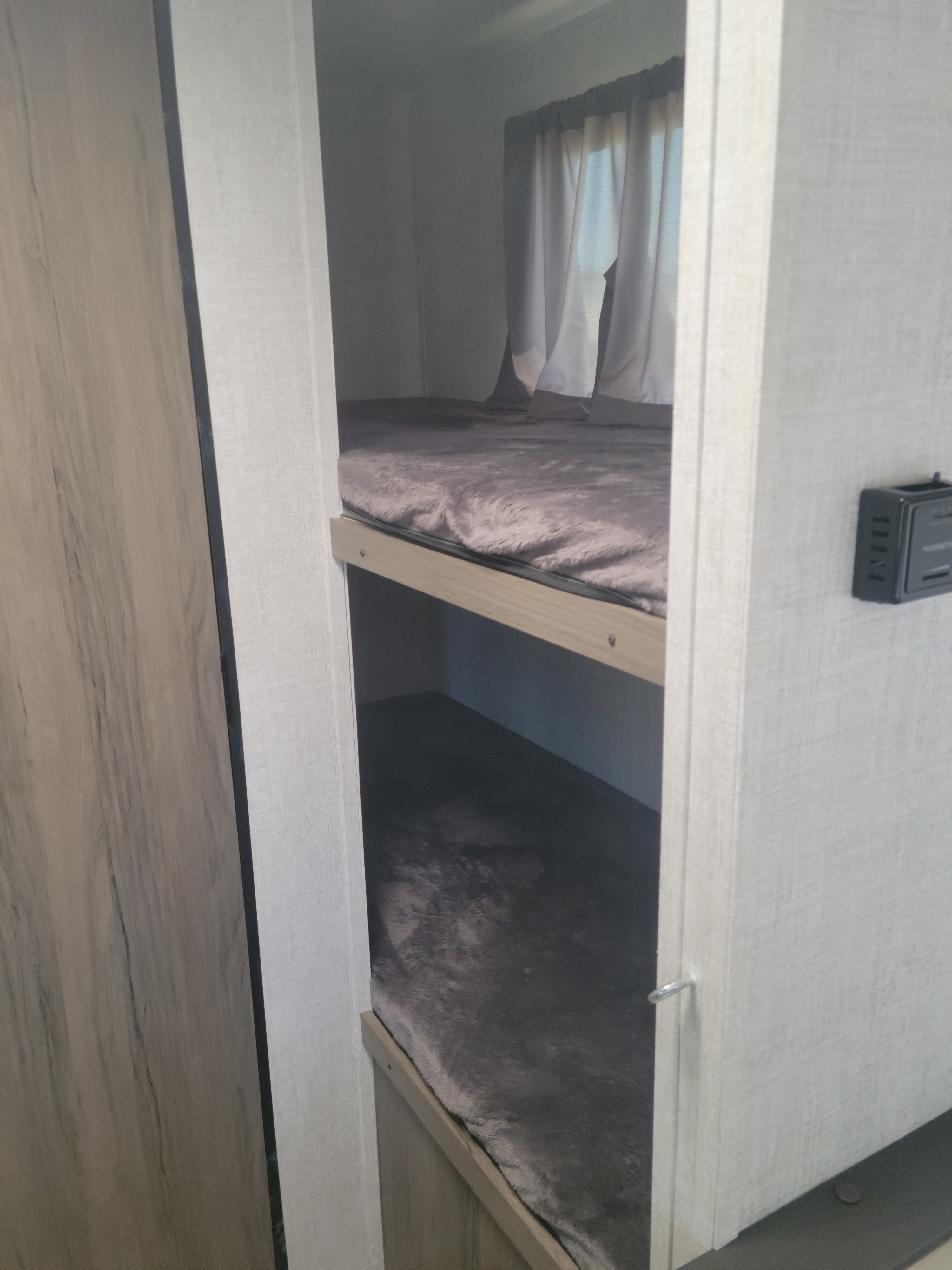 Cozy RV rental bunk beds with plush mattresses, window curtains, and interior controls shown.. Gulf Stream Ameri-Lite Super Lite 2021