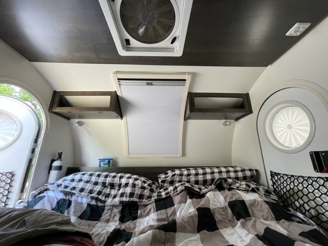 Inside a comfy RV rental: bed with plaid bedding, overhead shelves, & windows for natural light.. NuCamp T@G MAX XL BOONDOCK 2021