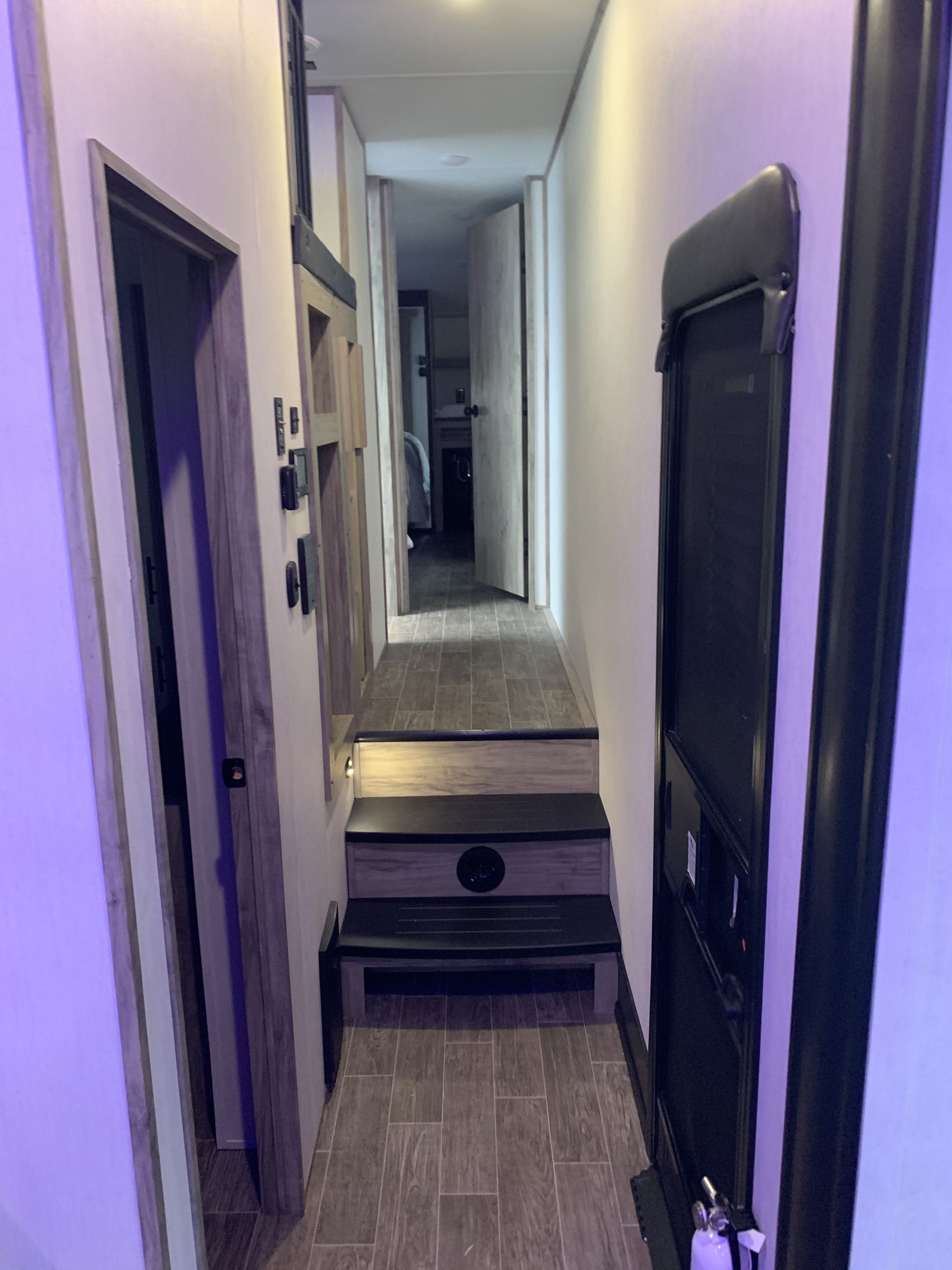 Cozy RV rental interior: A modern hallway with steps leading down to a bedroom, highlighting a functional living space.. Forest River Cherokee Arctic Wolf 2022