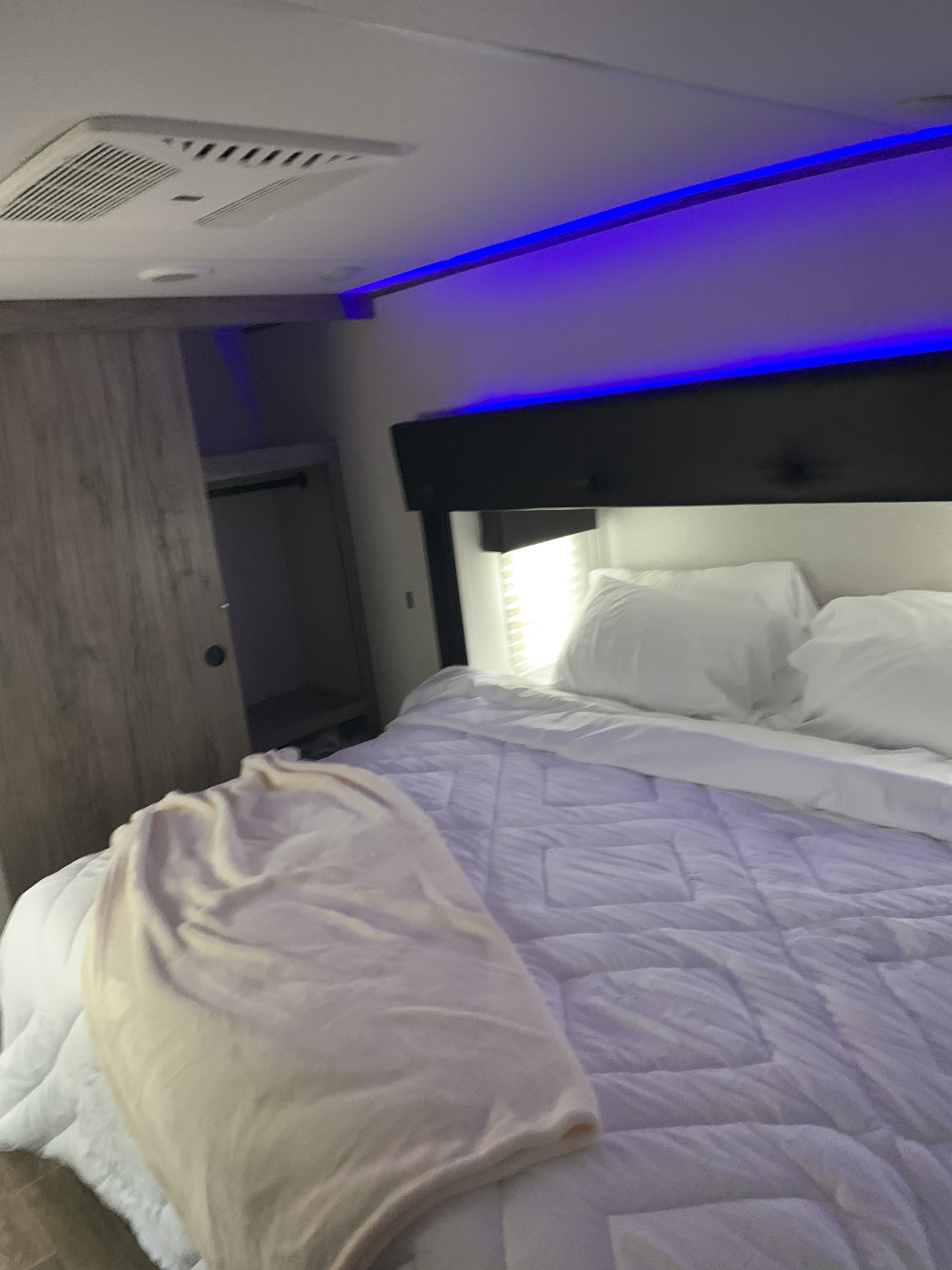 Cozy RV rental bedroom featuring a comfy bed, blue LED lights, a closet, and ceiling AC vent for comfort.. Forest River Cherokee Arctic Wolf 2022