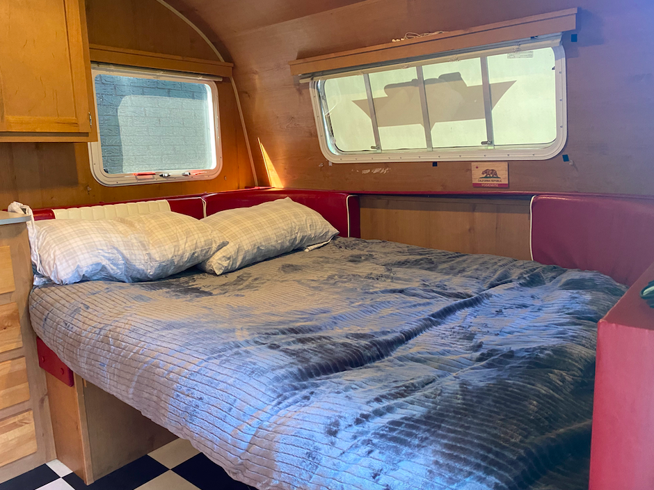 Cozy RV rental interior with a comfortable bed, red cushions, wood walls, and a checkered floor.. Riverside RV Retro 2017