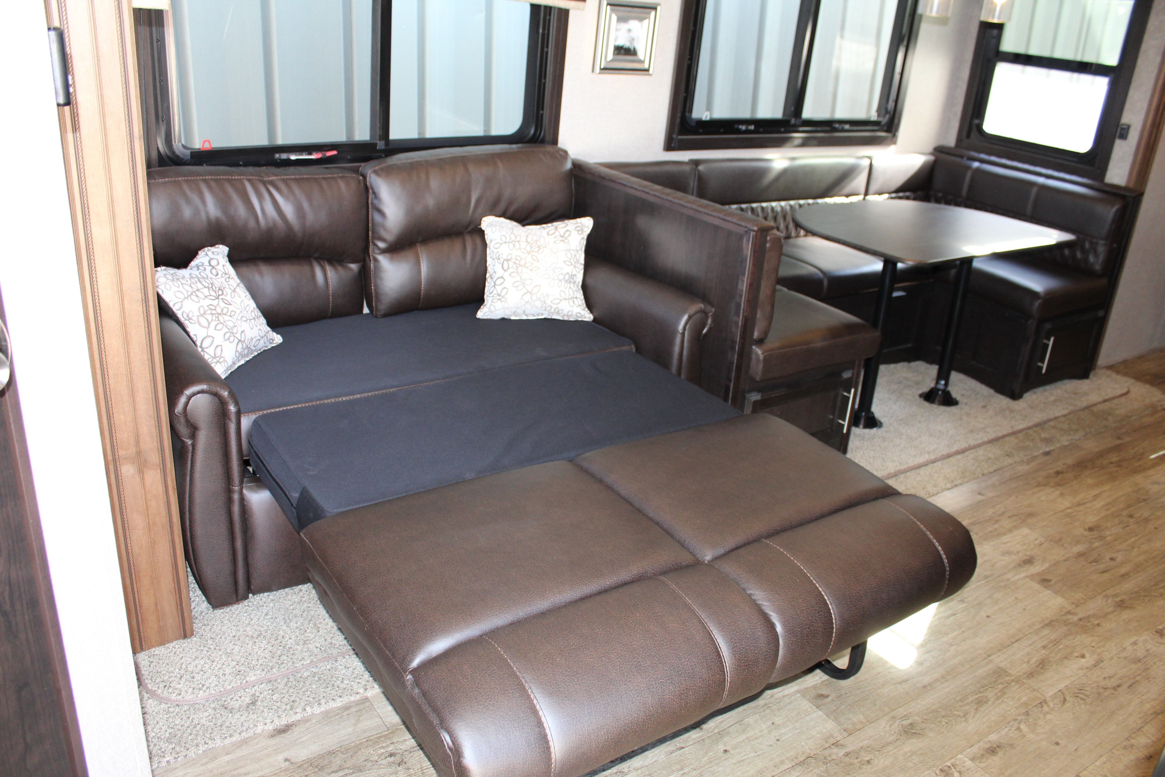Comfortable RV rental interior: brown leather sofa converts to a bed, U-shaped dinette & table. Perfect for your next trip.. Jayco 284BHOK 2019