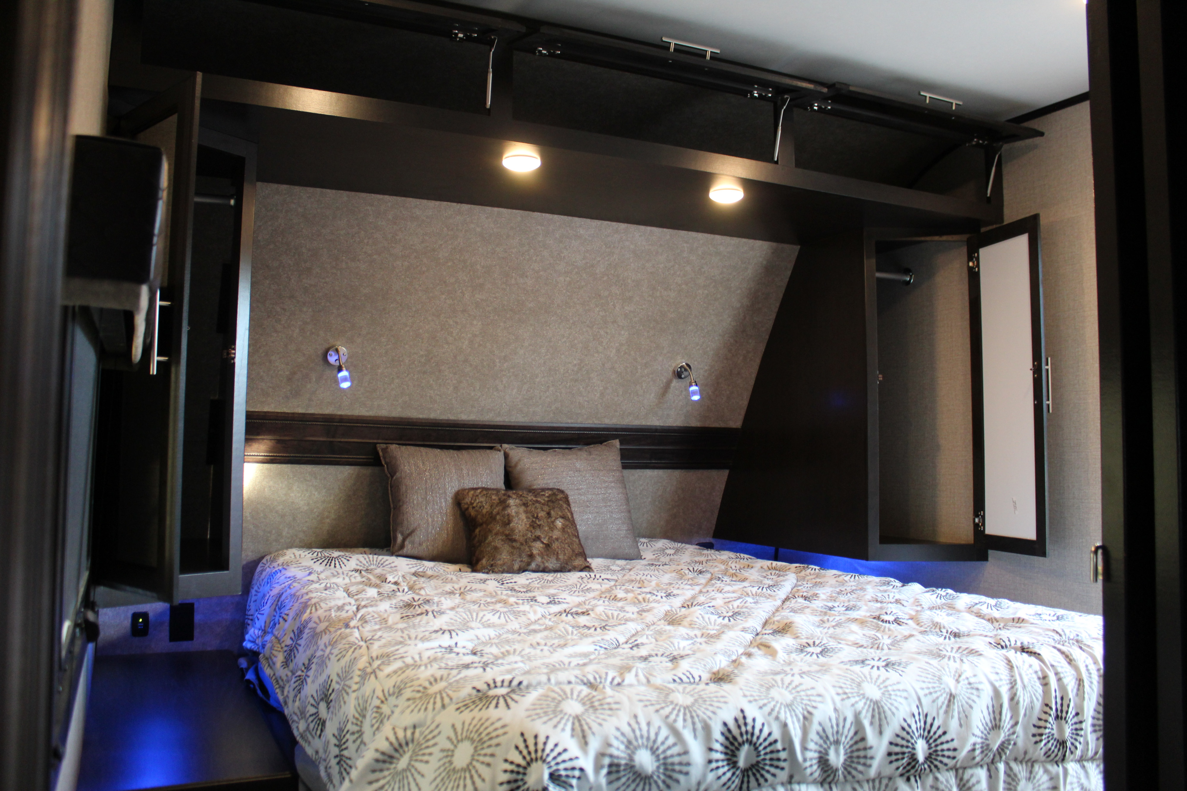 Experience comfort in this RV rental's modern bedroom, featuring overhead storage, accent lights, and a cozy bed.. Jayco 284BHOK 2019
