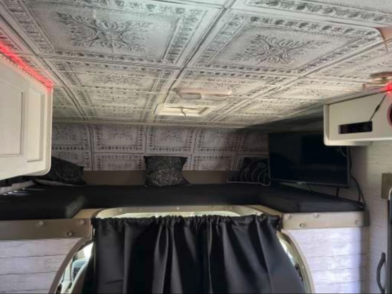 RV rental's custom interior features a decorative ceiling, elevated bunk bed, TV, and black privacy curtains.. Forest River Coachmen Freelander 2010