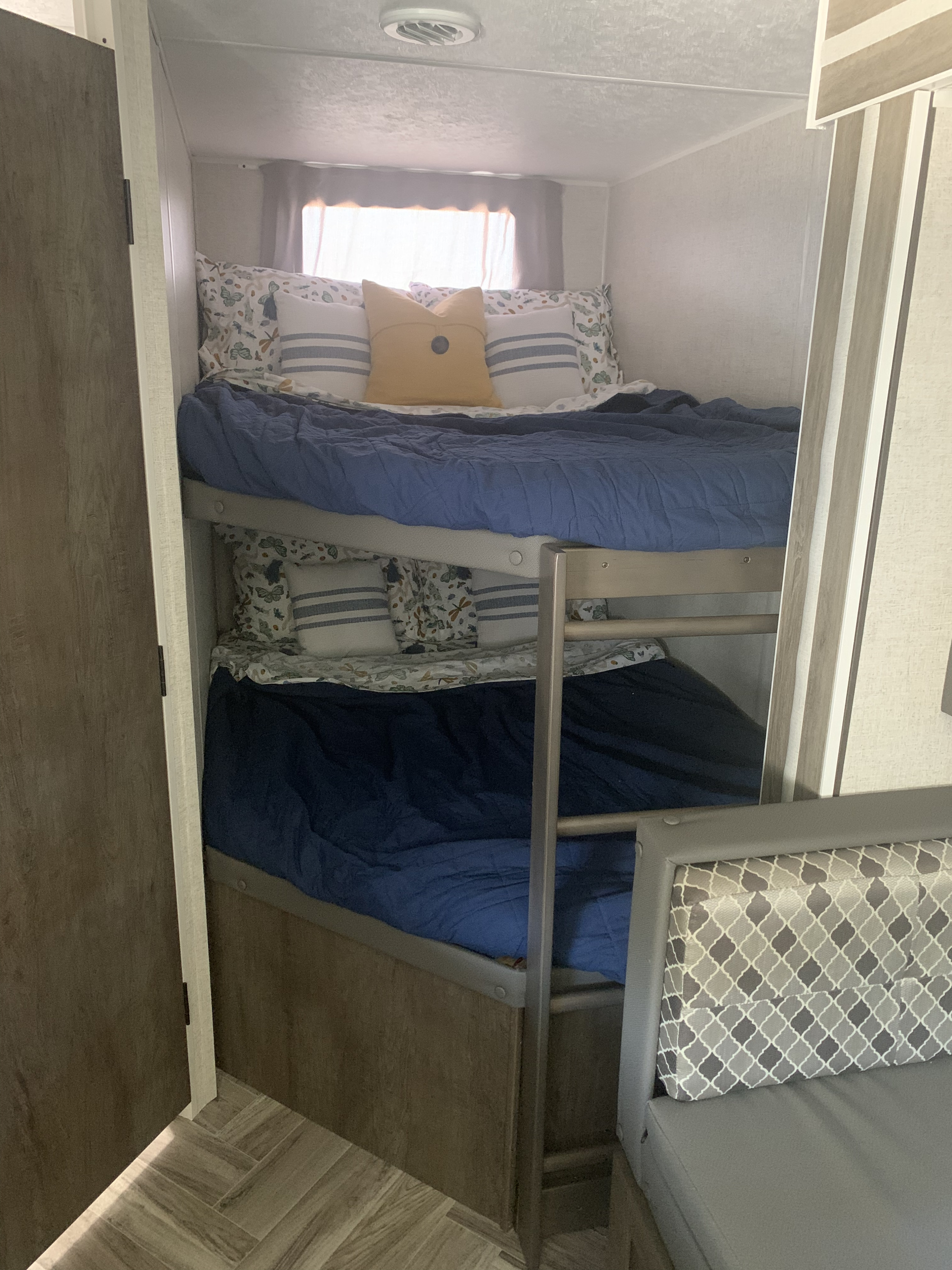 Cozy RV rental interior with bunk beds, blue bedding, and a comfortable patterned seating area.. Forest River EVO T2400BH 2021
