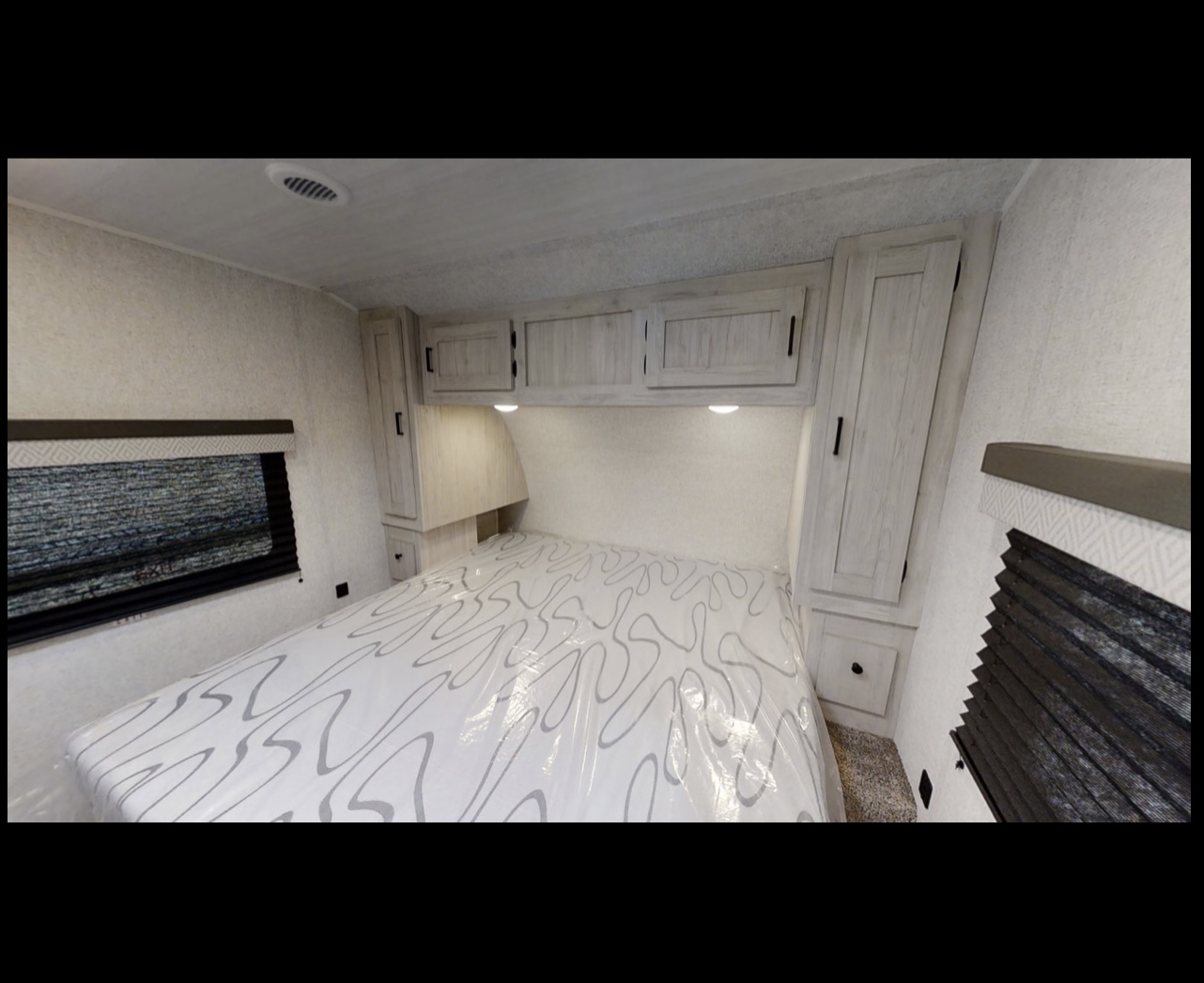 RV rental bedroom: Features a comfy bed, overhead cabinets, and windows. Ideal for travel comfort and rest.. East to West Della Terra 2022