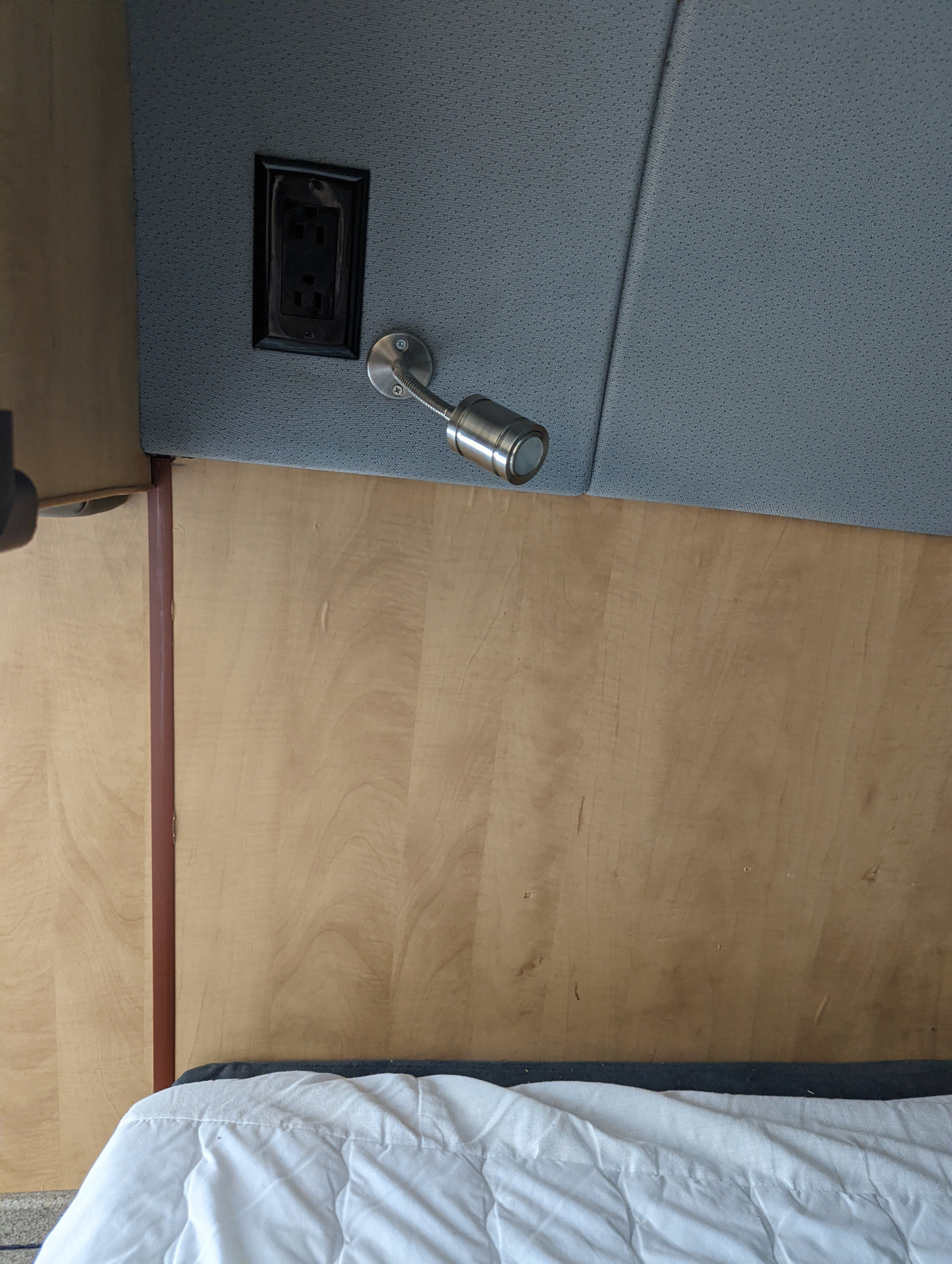 RV rental sleeping area: a wooden headboard, gray fabric panel with an outlet & flexible reading lamp.. Freightliner Sprinter Van 2012