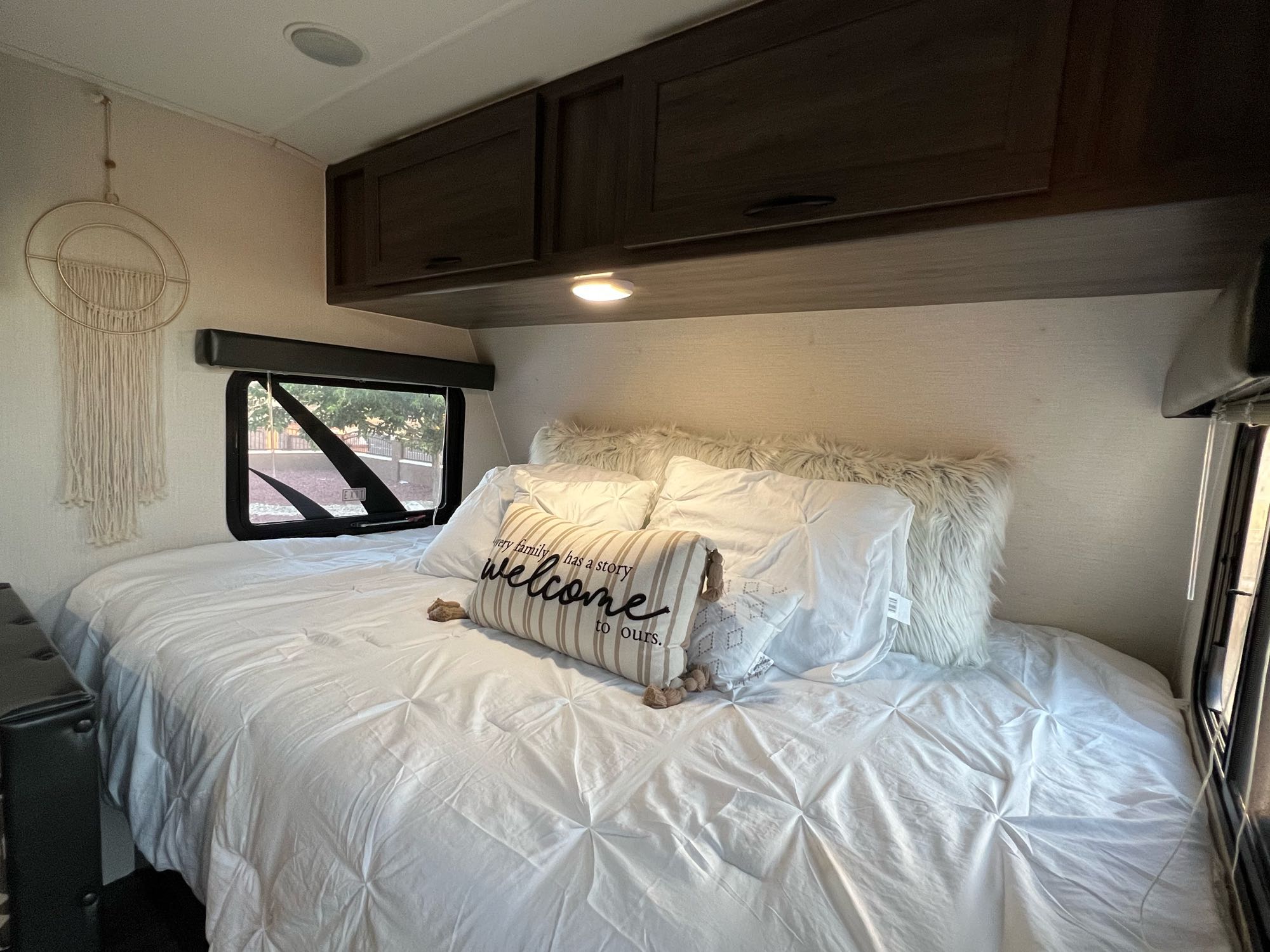 Discover a cozy RV rental bedroom featuring a large bed with white linens, a welcome pillow, and storage cabinets.. Pacific Coachworks Pacifica XL 2020