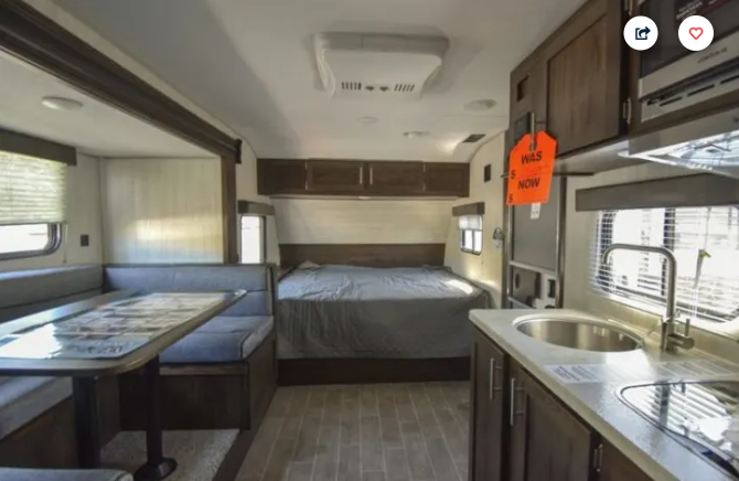 An RV rental interior reveals a clean, modern space with a dinette, kitchen, and rear bedroom area.. Forest River Cherokee Wolf Pup 2020