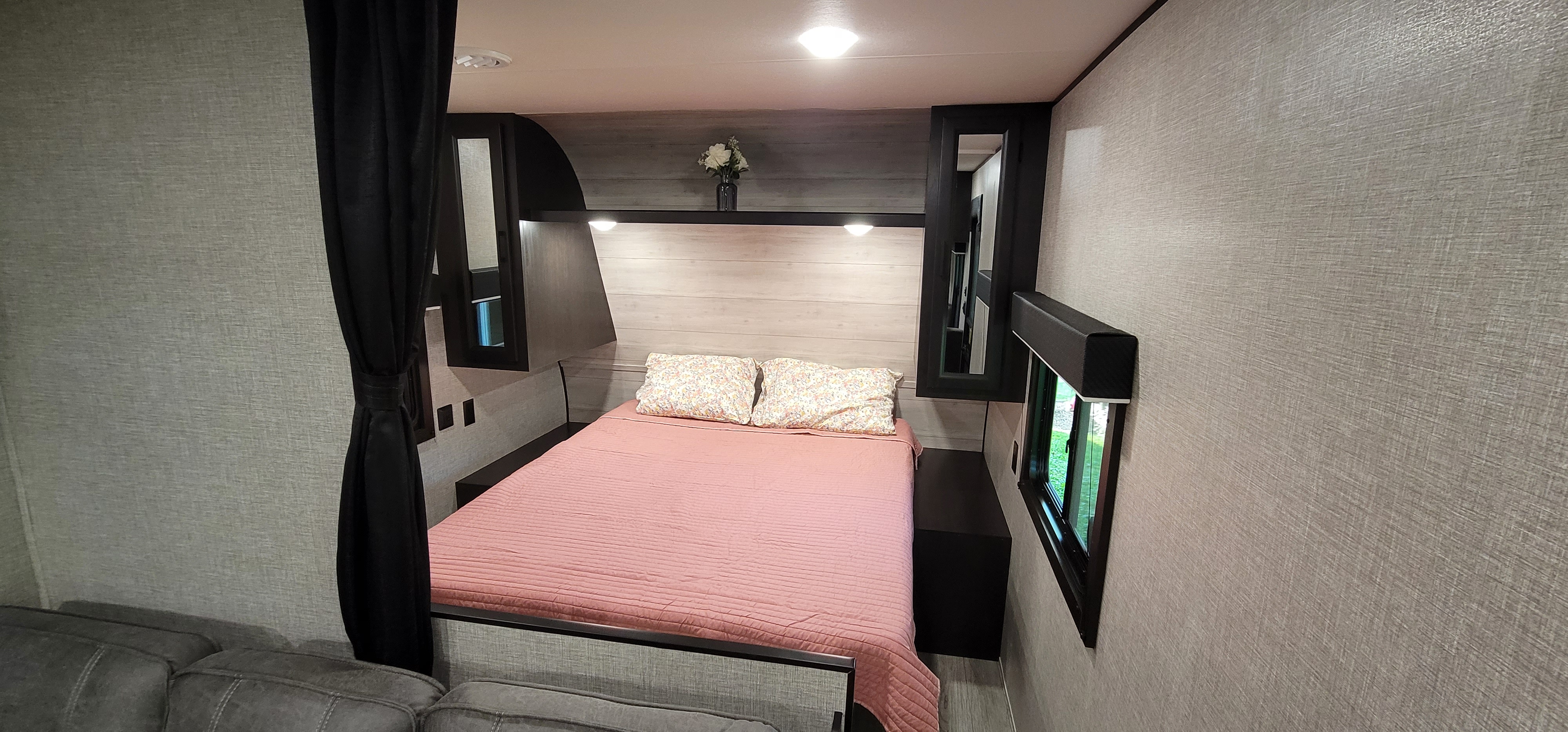 Cozy RV rental bedroom featuring a pink bed, patterned pillows, overhead storage, and a window, ideal for road trips.. Jayco Jay Flight SLX 8 264BH 2022