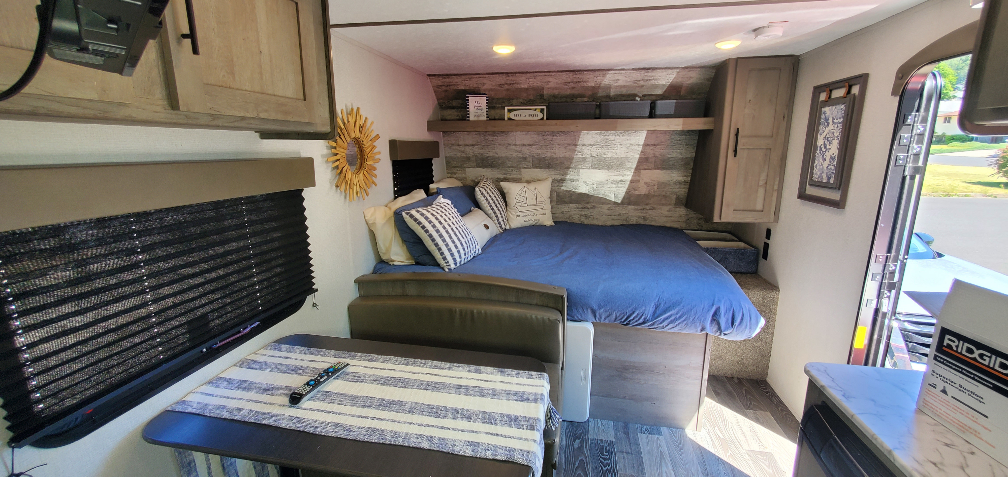 Inside this RV rental: a comfy bed, dining nook, and window with blinds create a cozy mobile home.. Keystone RV Springdale 2021