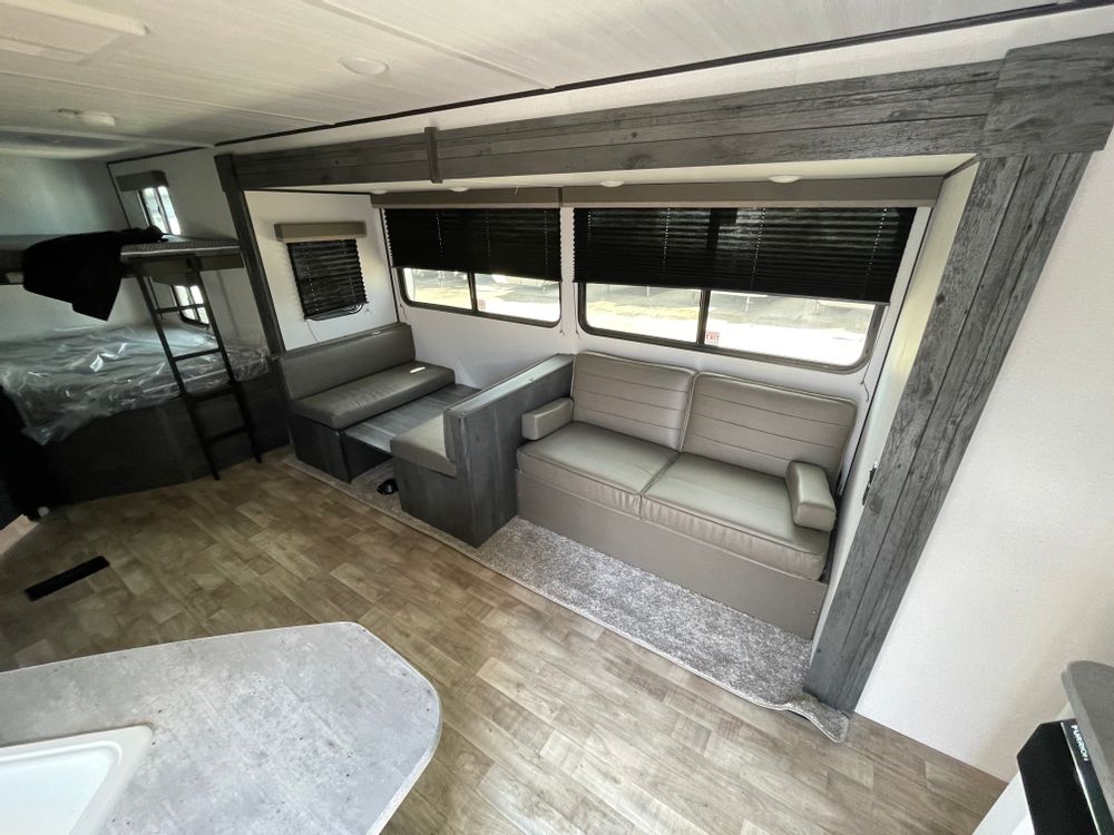 Modern RV rental interior: bunk beds, dinette, and a sofa provide comfortable living space.. Keystone Hideout 2022