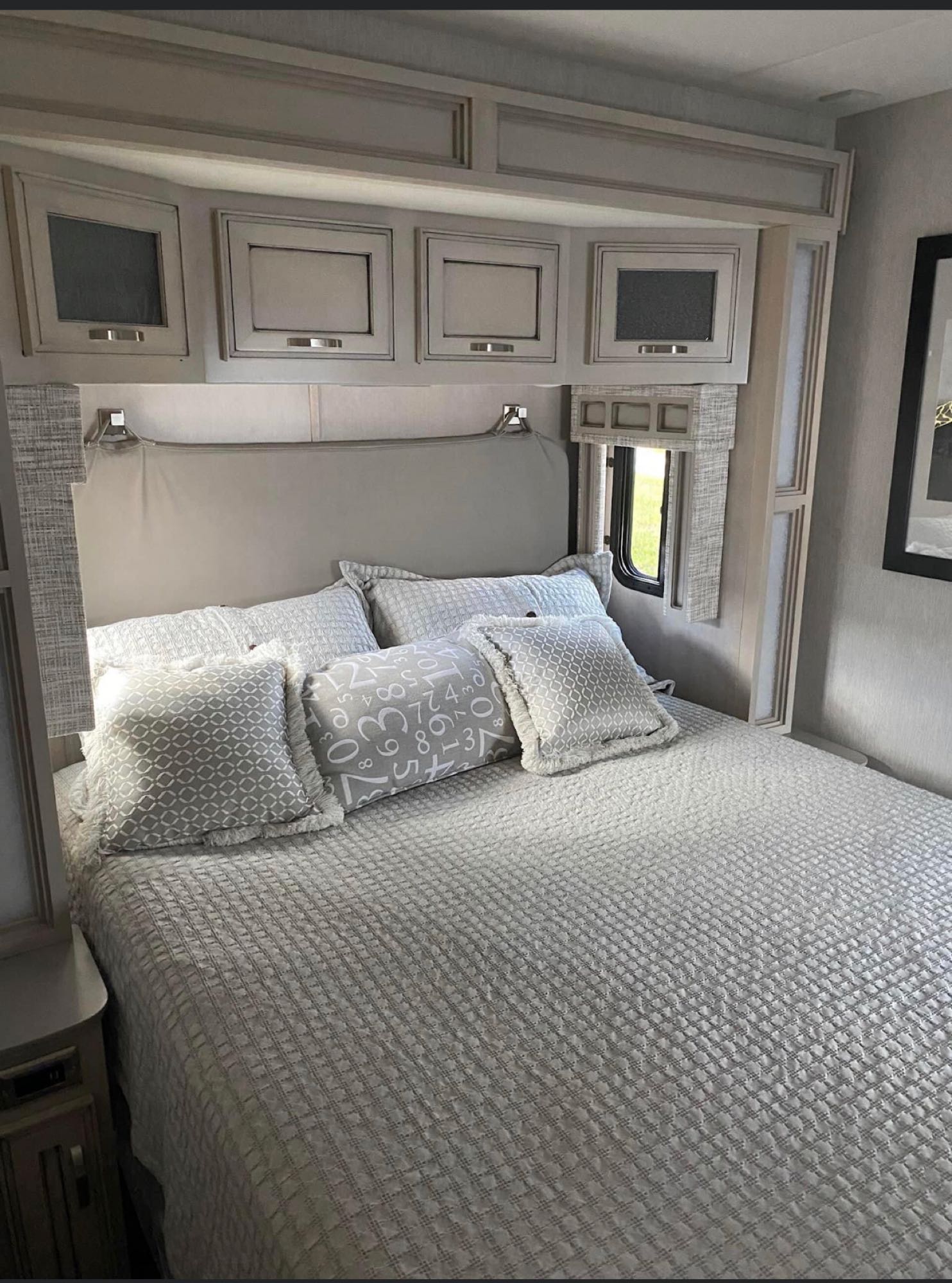 Comfortable RV rental bedroom with quilted bed, overhead cabinets, and soft pillows, offering a cozy sleeping area for travel.. Newmar Canyon Star 2022