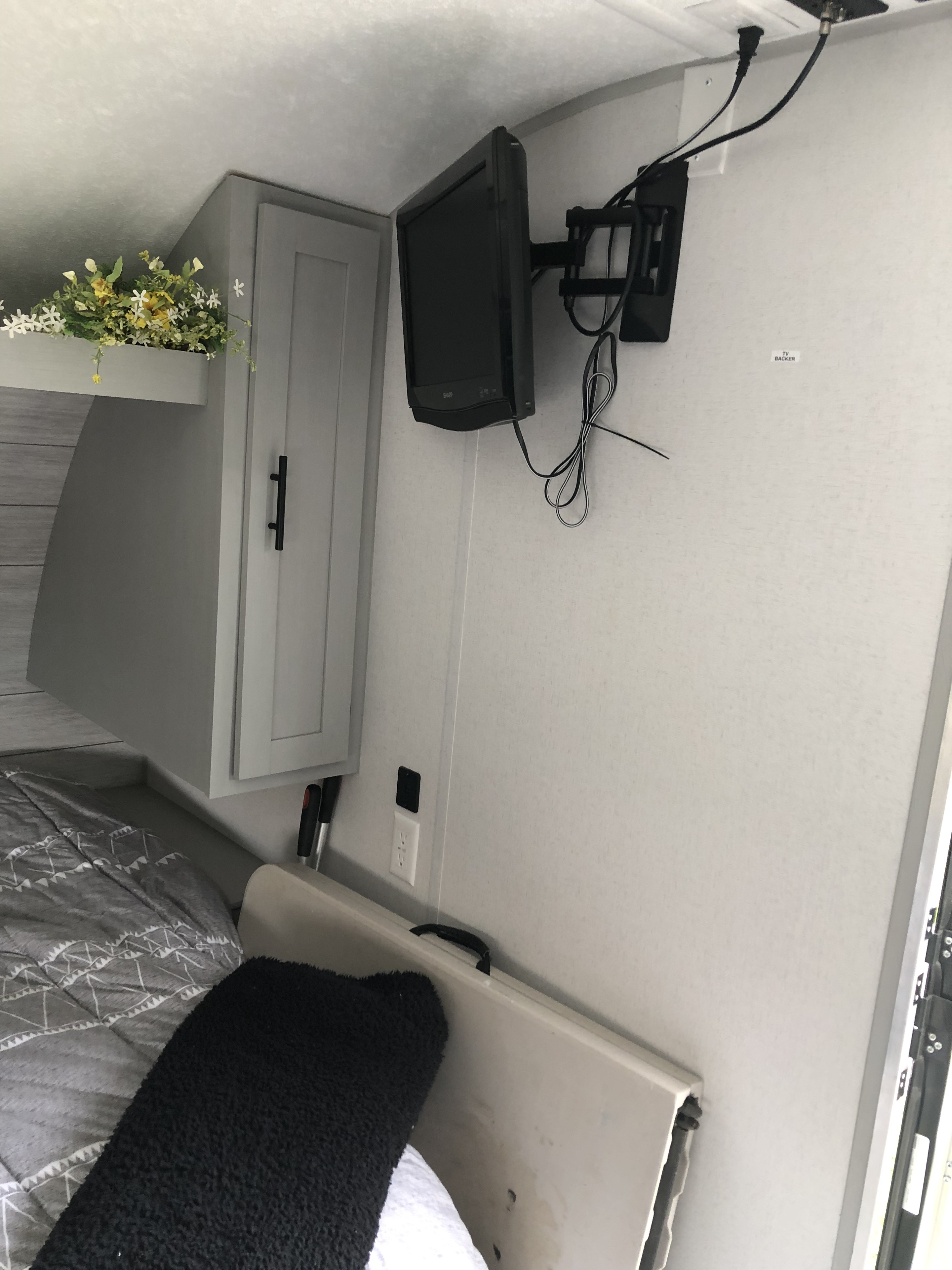 RV rental bedroom featuring a wall-mounted TV, overhead storage cabinet, and bed. Ideal for comfortable travel.. Forest River Wildwood 2021