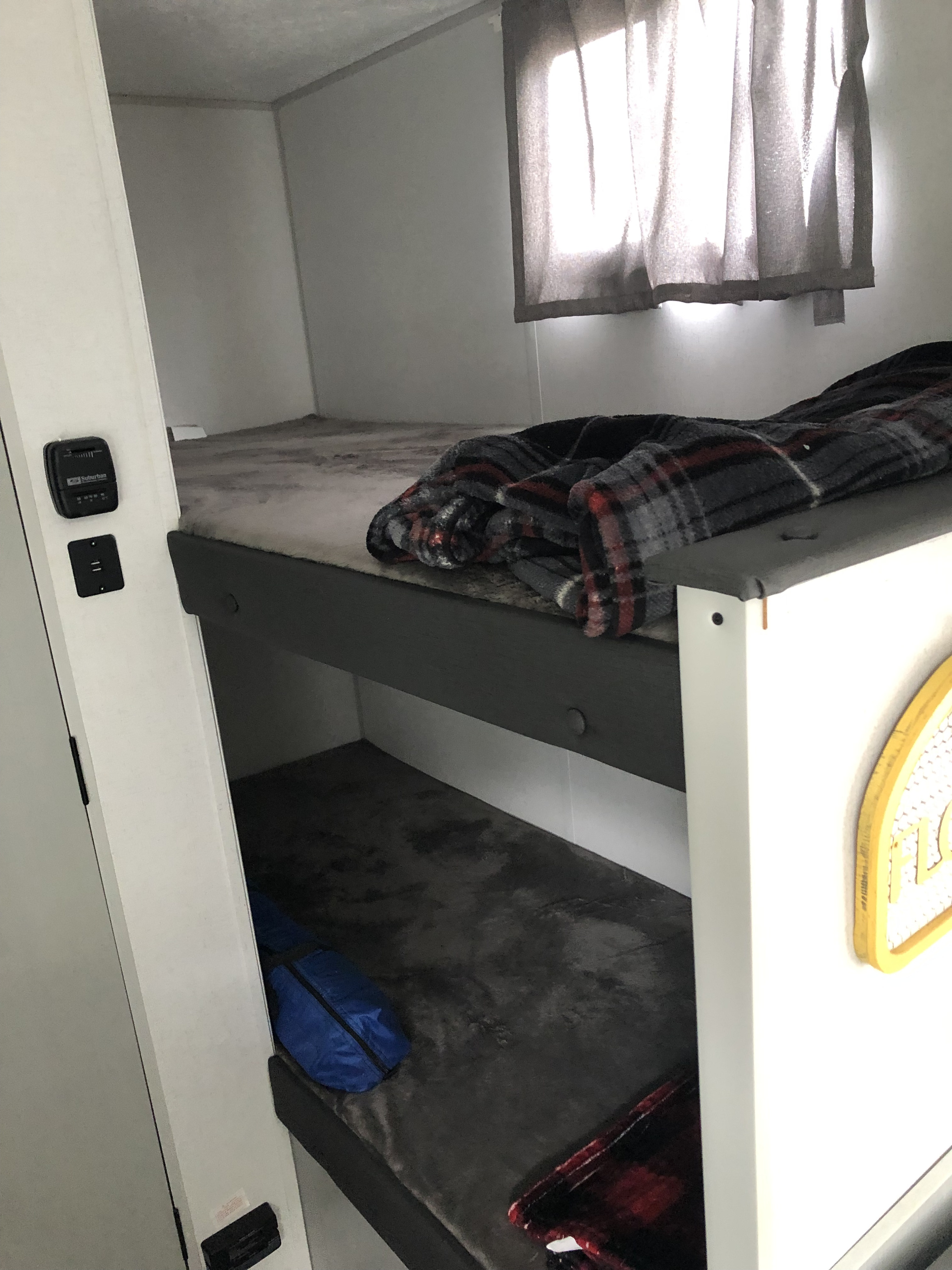 RV rental: Bright interior with cozy bunk beds. The top bunk has a plaid blanket, the bottom for bedding and a blue bag.. Forest River Wildwood 2021