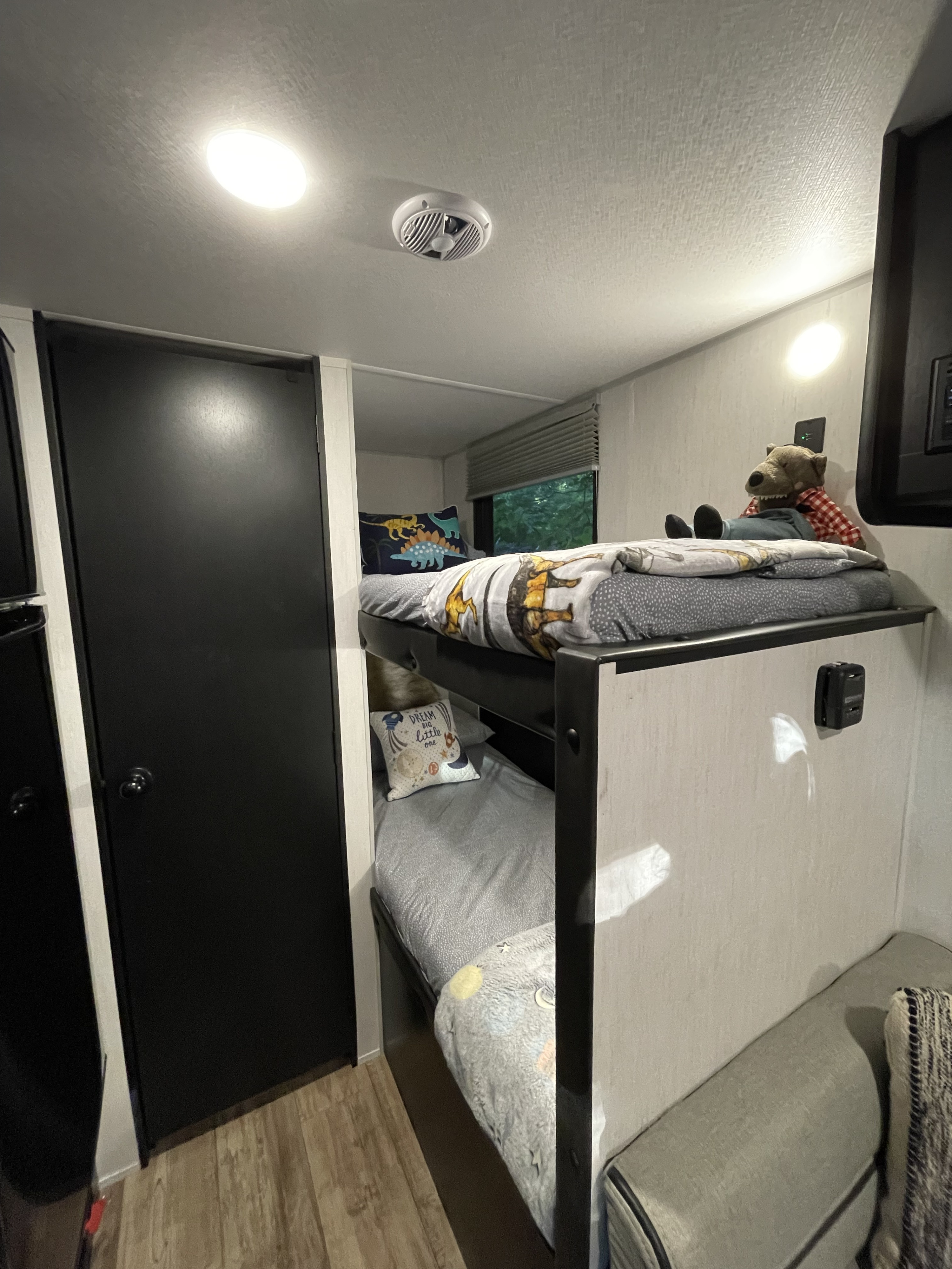Inside an RV rental: a comfortable bunk bed sleeping area with soft linens and a playful stuffed animal.. Forest River Cherokee Wolf Pup Black Label 2022