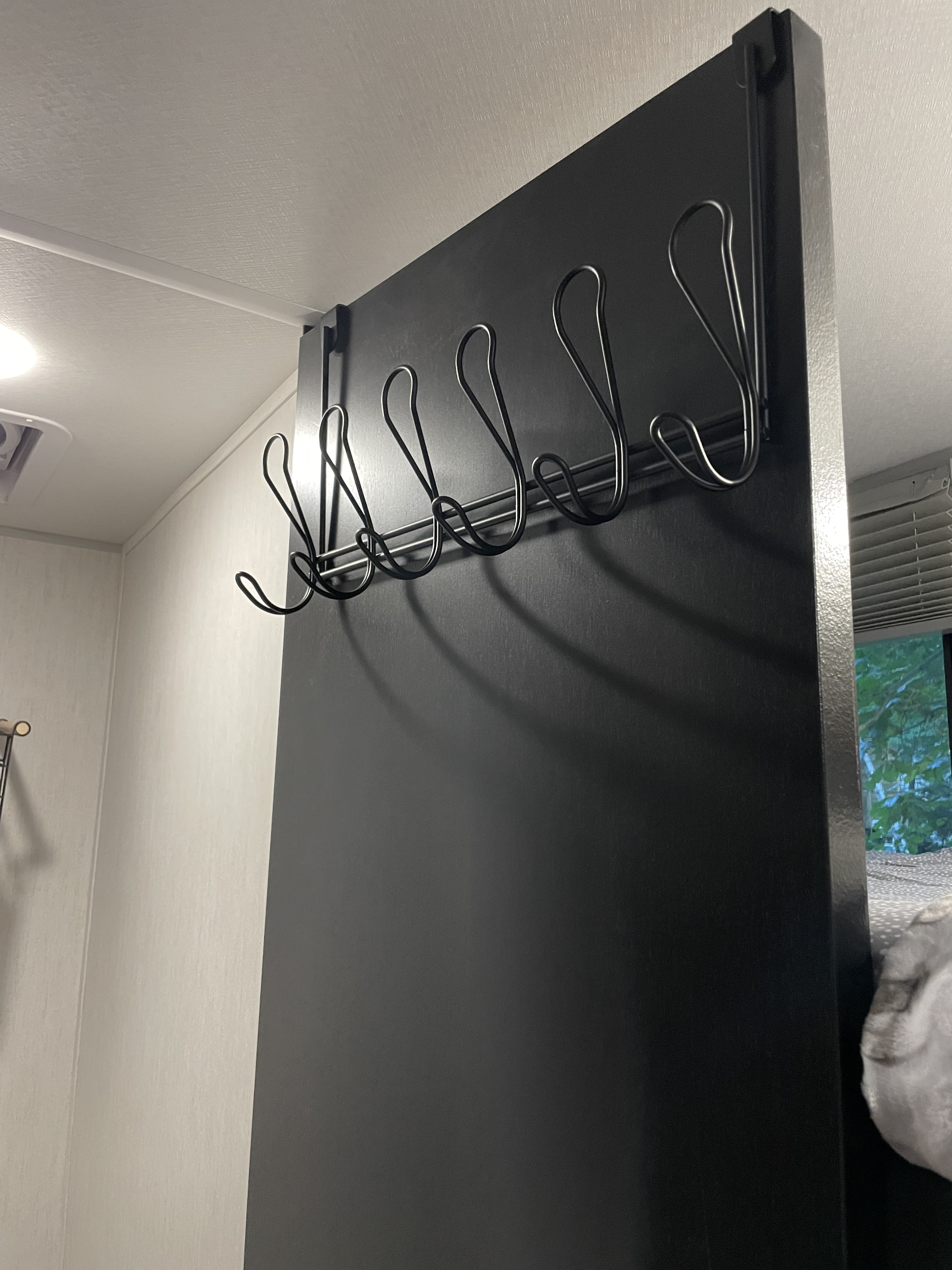 Black over-the-door hooks provide efficient storage within this RV rental, enhancing organization in compact camper spaces.. Forest River Cherokee Wolf Pup Black Label 2022