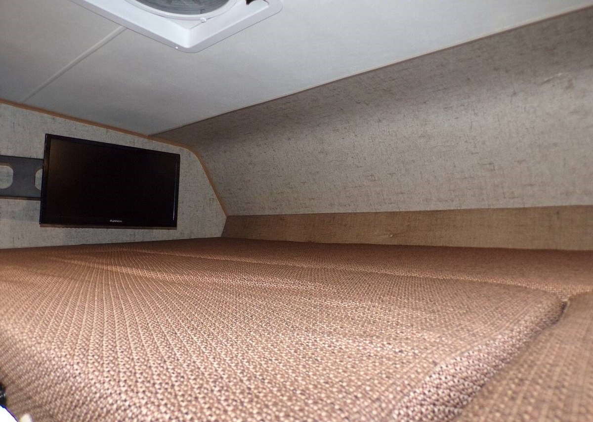Cozy RV rental cab-over bed with a mounted TV and overhead vent, offering a comfortable sleeping area for travels.. Forest River Coachmen Leprechaun 2018