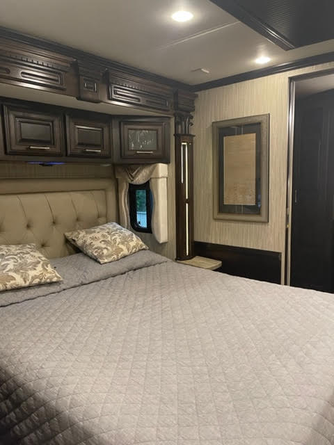 Comfortable RV rental bedroom featuring a spacious bed, overhead storage, and warm lighting, ideal for a cozy travel stay.. Other Other 2017