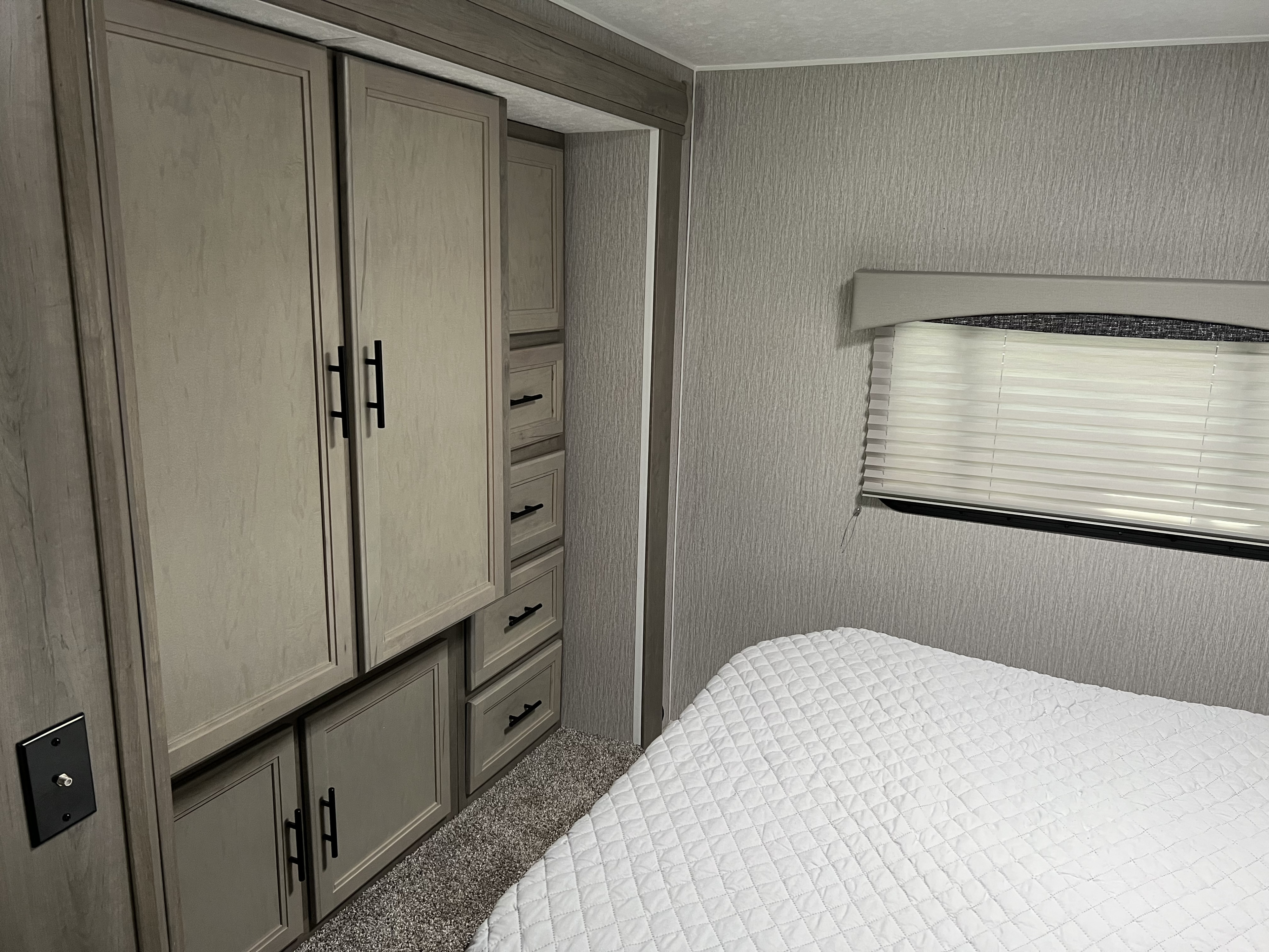 Compact RV rental bedroom with ample storage cabinets, comfy bed, and modern finishes.. Forest River Coachmen Freelander 2023
