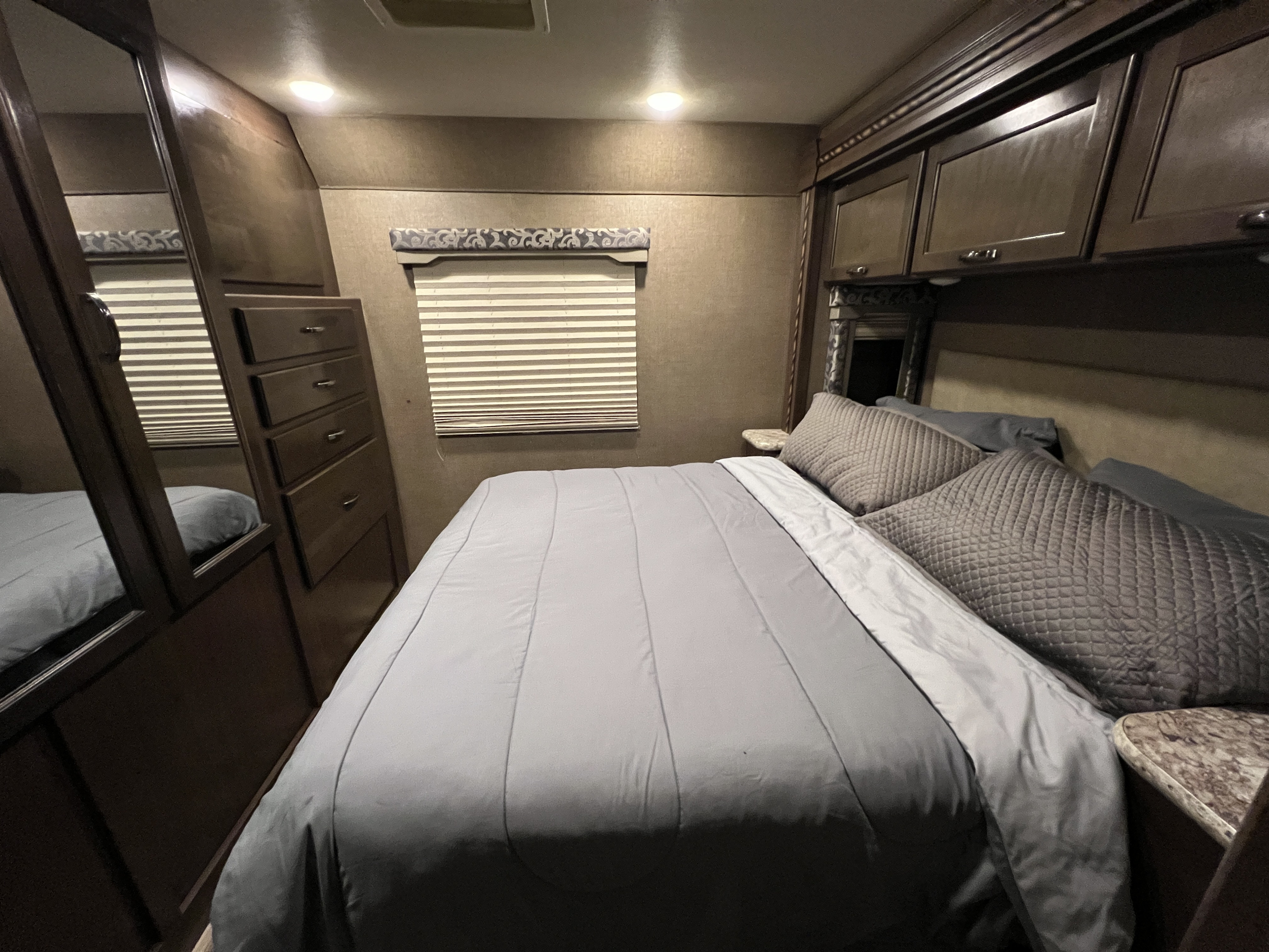 Experience comfort in your RV rental with this cozy bedroom featuring a queen bed, ample storage, and a window for natural light.. Thor Four Winds 2018