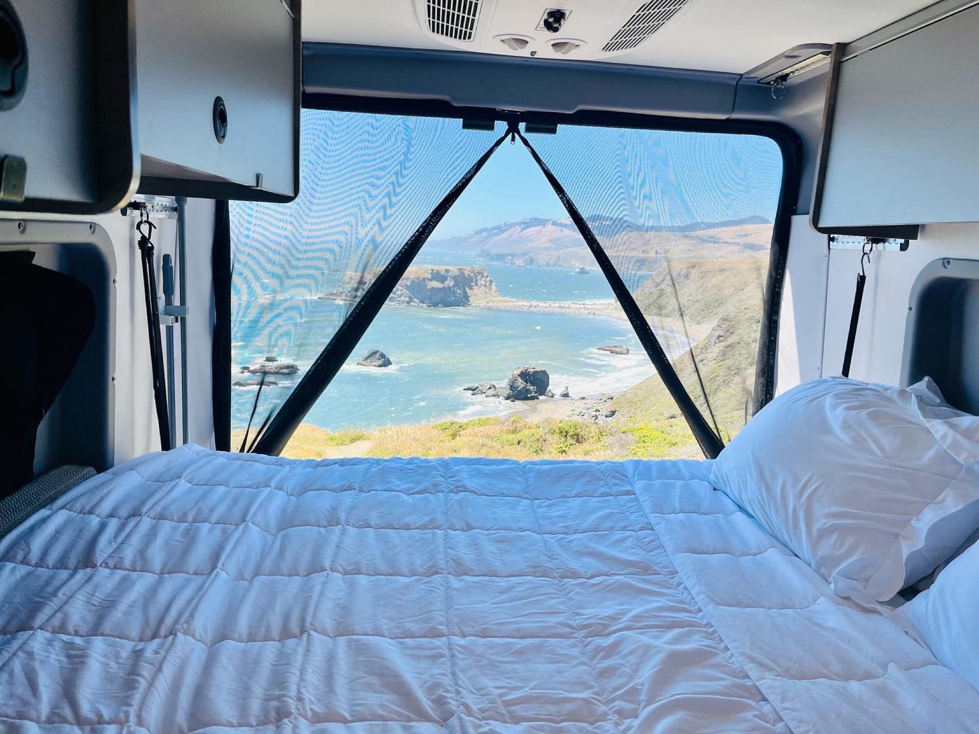 This RV rental offers a comfy bed with a stunning ocean view through the mesh screen. Ideal for travel!. Winnebago solis 2022