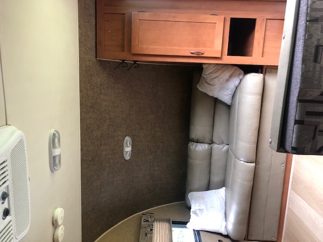 RV rental interior showcasing light brown dinette seating, overhead wooden cabinets, and wall controls.. Forest River Cherokee 2015