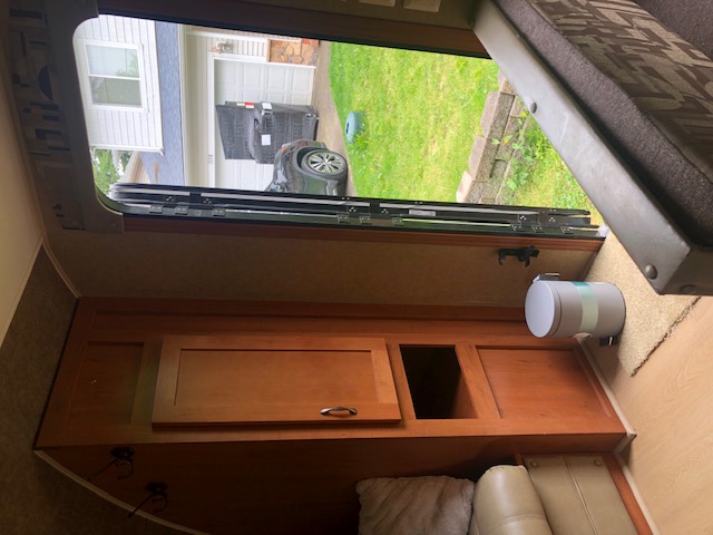 Inside an RV rental, looking out the open door. Features include a portable toilet, built-in storage, and seating.. Forest River Cherokee 2015