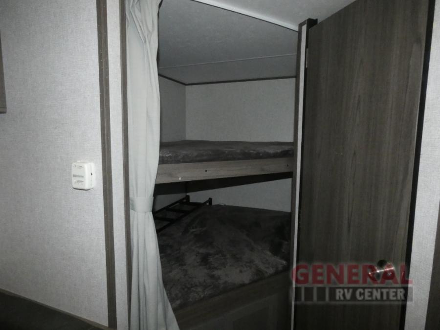 Interior of an RV rental showing stacked bunk beds with a privacy curtain, providing extra sleeping in a camper.. Dutchmen Kodiak Ultra Lite 2021