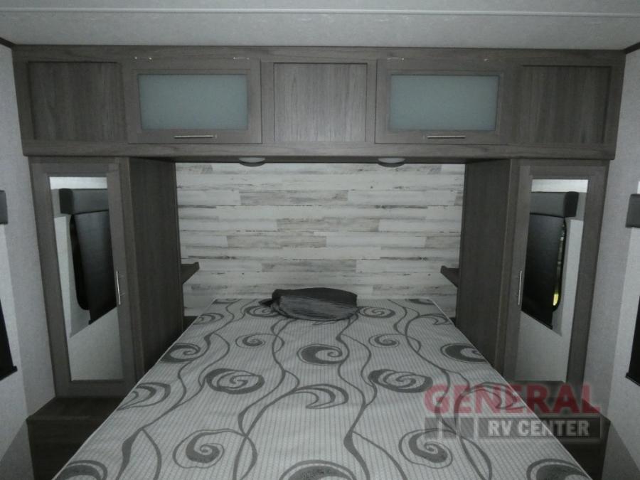 RV rental bedroom featuring a patterned bed, overhead cabinets, and side storage, perfect for your journey.. Dutchmen Kodiak Ultra Lite 2021