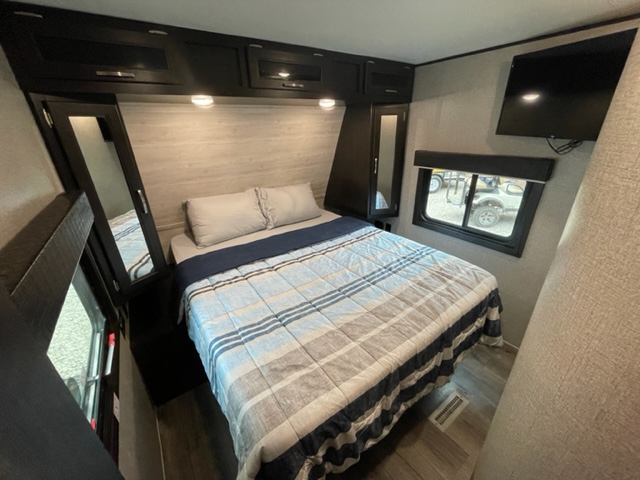 RV rental bedroom: large bed, dark overhead cabinets, a mirror, TV & window. Ready for adventure.. Jayco Jay Flight 2021