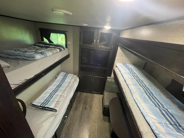 Spacious RV rental interior featuring multiple bunk beds and a dining area, ideal for family travel.. Jayco Jay Flight 2021
