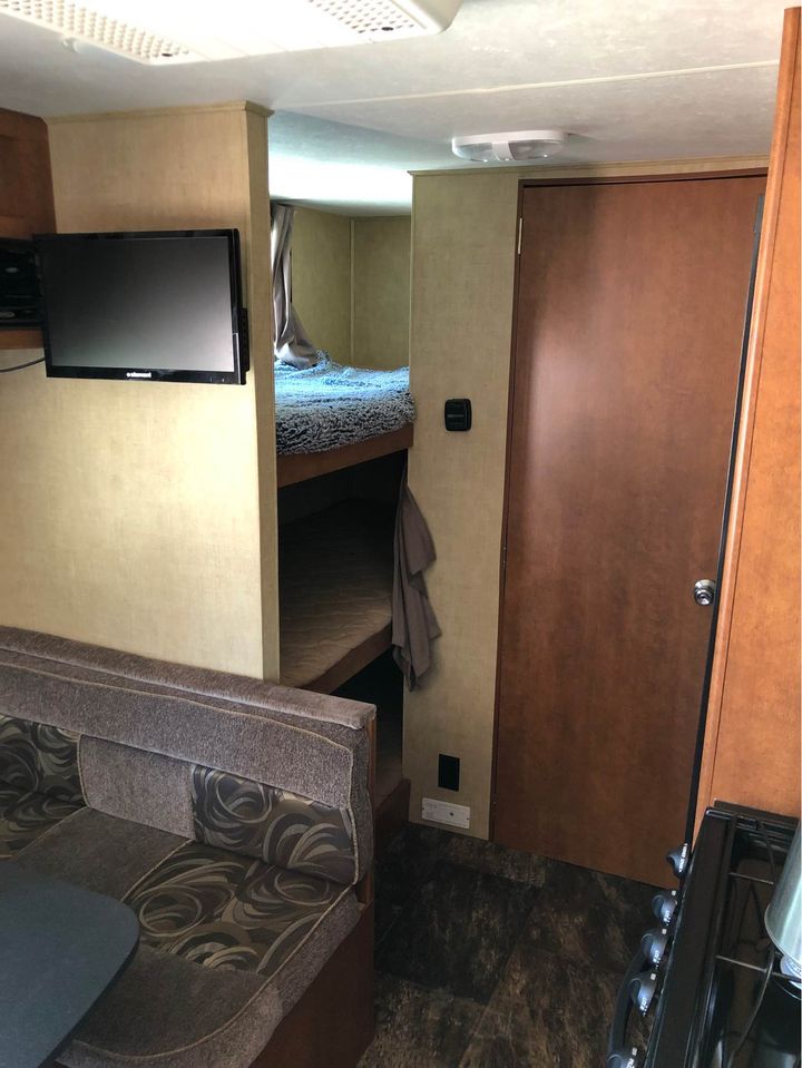 This RV rental interior features bunk beds, a dinette, wall-mounted TV, and kitchen. Perfect family camper space.. Forest River Shasta Freeport 2012