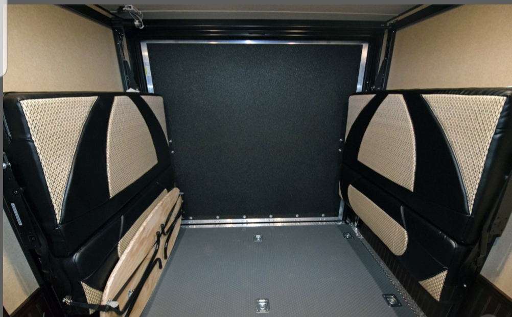 Inside an RV rental: versatile cargo area with fold-up black and beige benches/beds, showing flooring & back wall.. Forest River XLR HyperLite Toy Hauler 2016