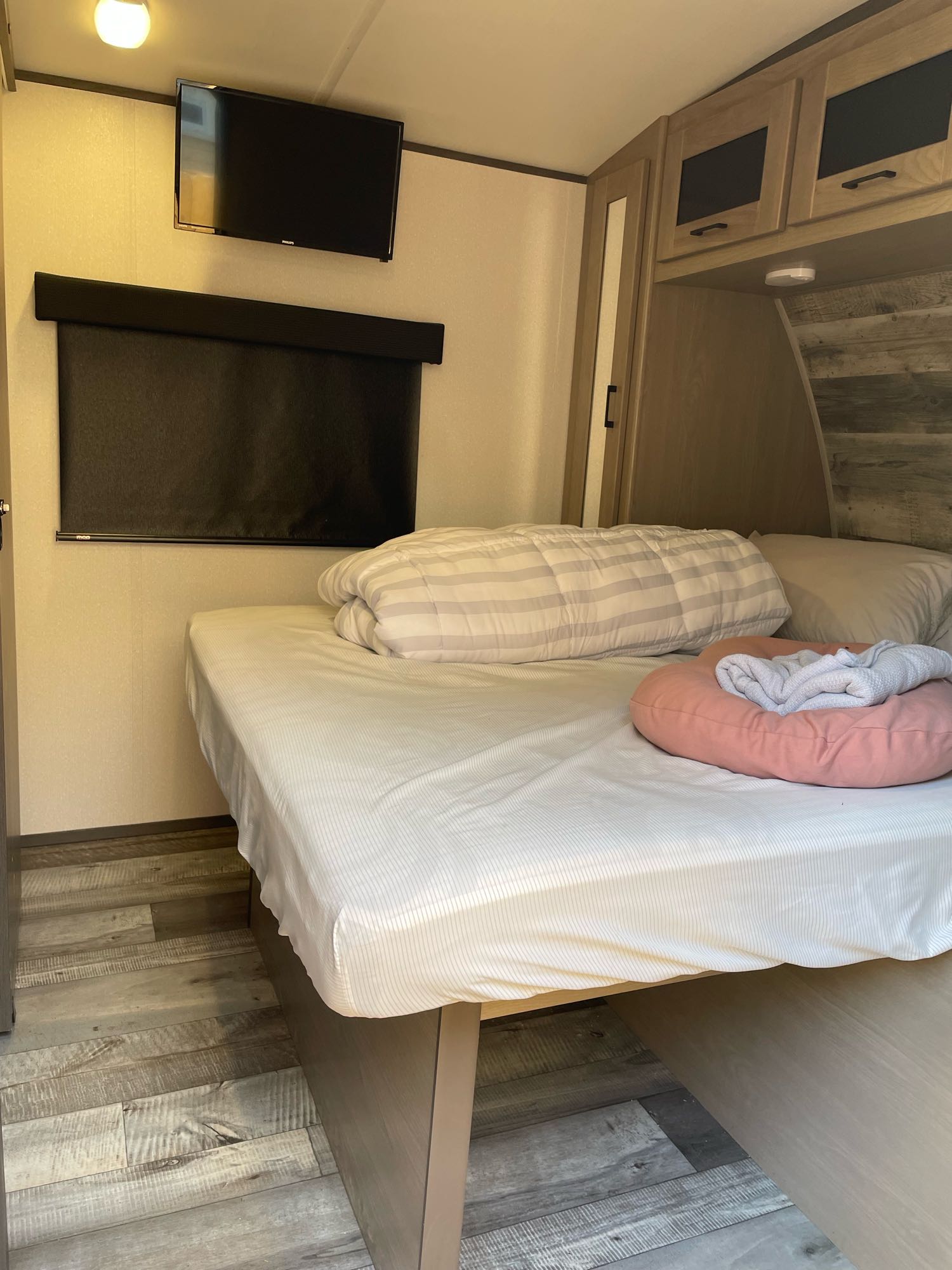 Relax in this RV rental bedroom: a comfy bed, wall-mounted TV, and storage for essentials, plus a window blind. Cozy travel awaits.. Heartland RVs Sundance Ultra Lite 2022