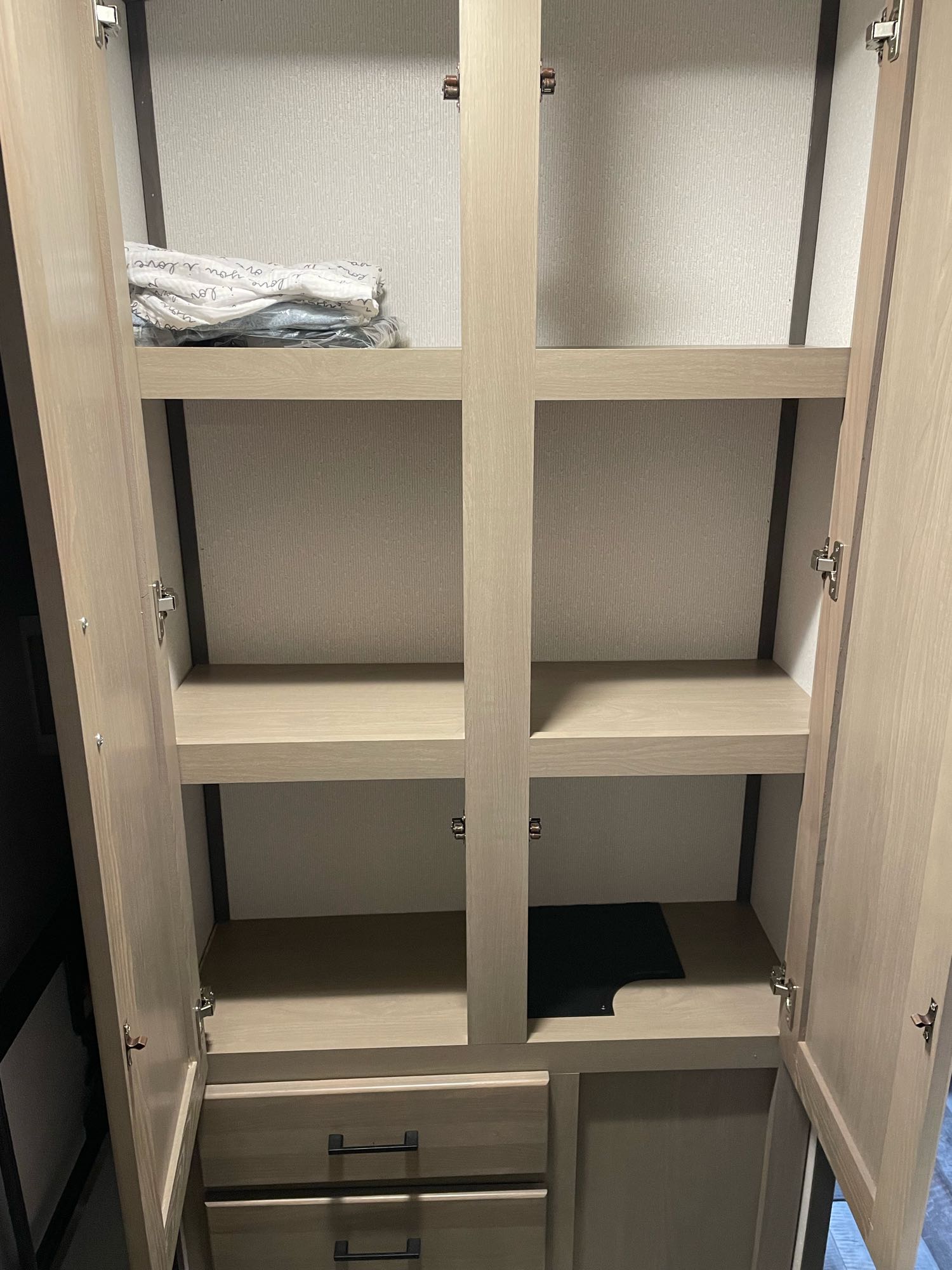 Open RV rental closet with light wood finish, adjustable shelves, and bottom drawers, offering ample storage for your trip.. Heartland RVs Sundance Ultra Lite 2022