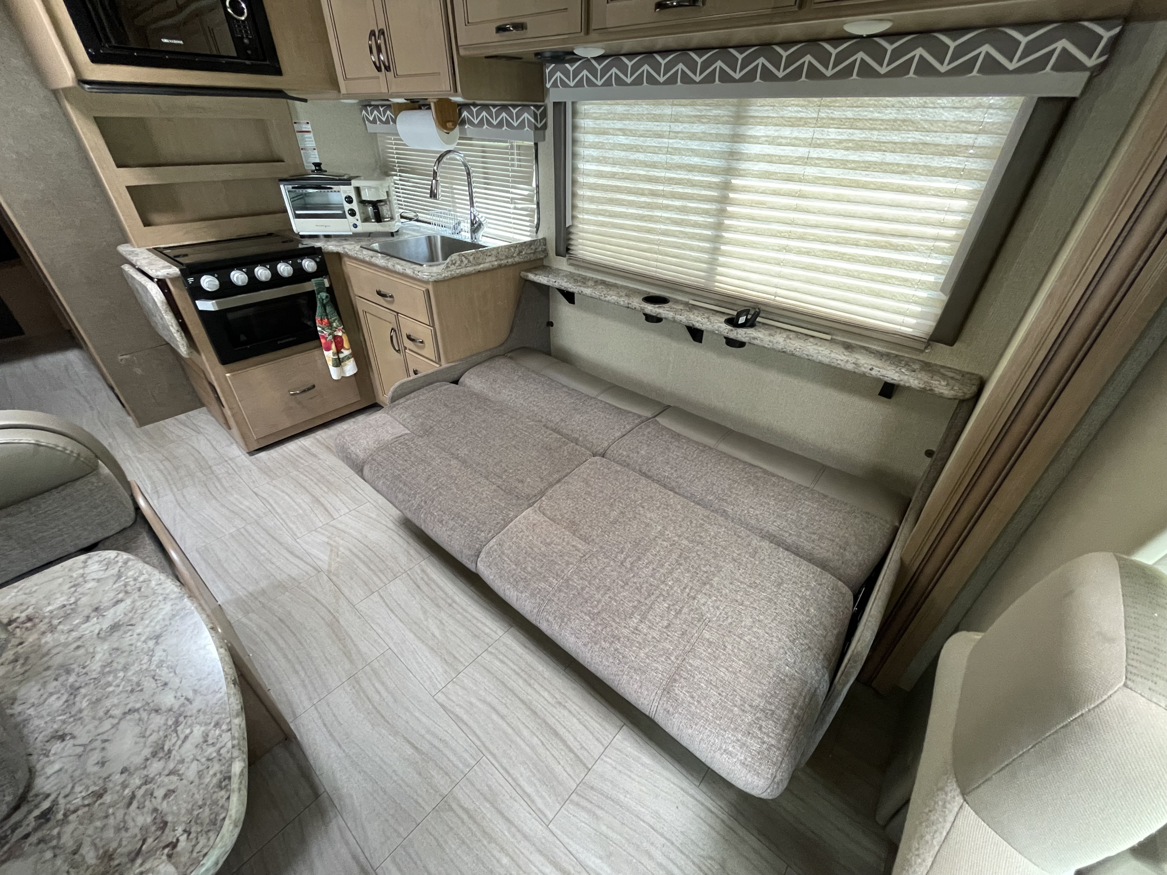 RV rental interior with a compact kitchenette, comfortable sofa bed, and dining space. Perfect for on-the-go living.. Thor Daybreak 2019