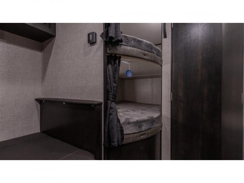 Cozy RV rental interior featuring bunk beds with privacy curtains, a convertible bench, and a dark wood cabinet.. Jayco Jay Series 2022