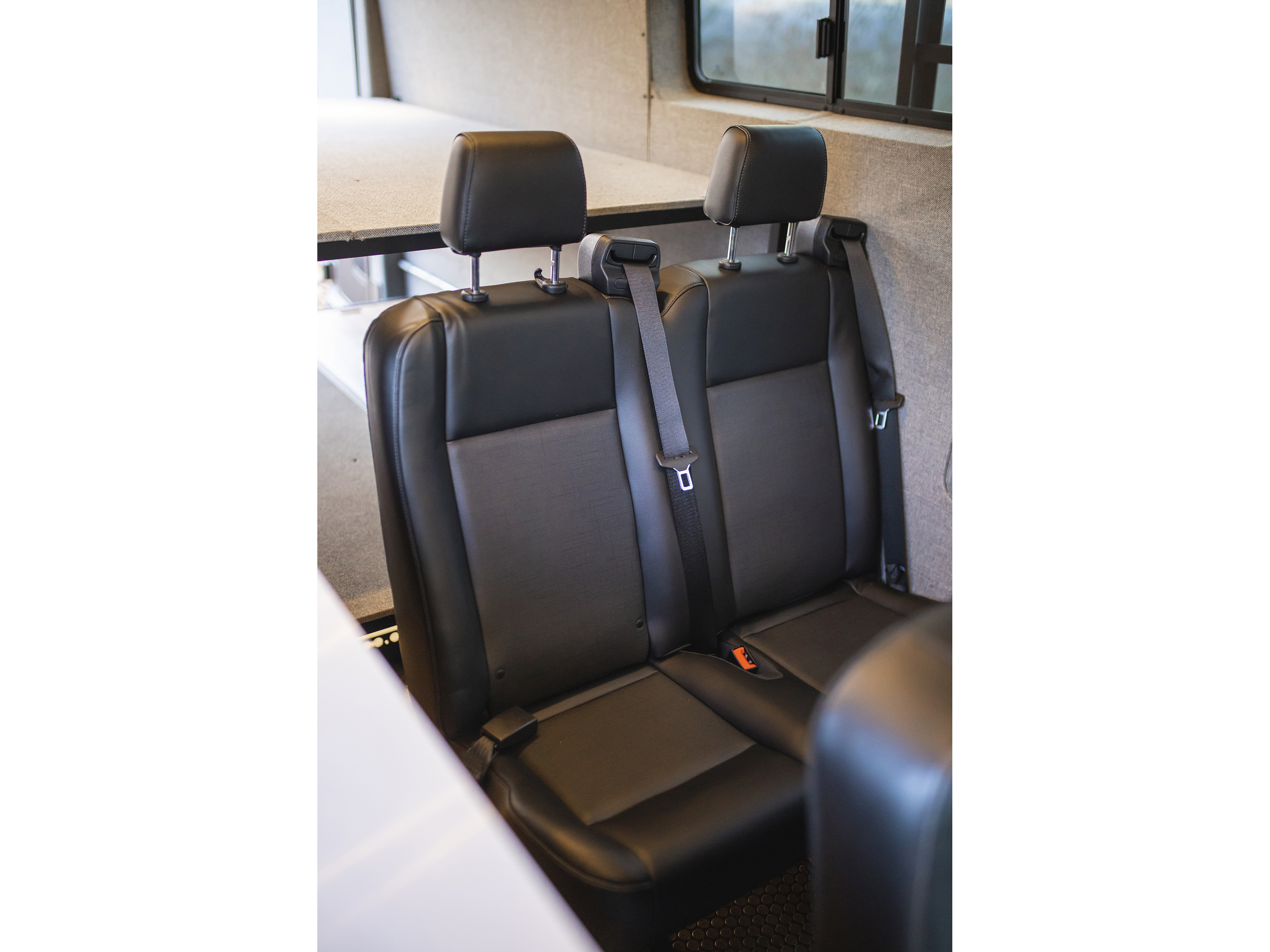 RV rental interior shows two black seats with seatbelts, a bunk bed, and window. Ideal for comfortable travel and adventure.. Ford Transit 2021