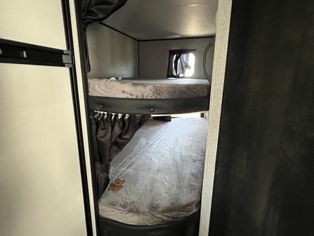 Explore this RV rental's cozy bunk beds! Perfect for family trips, featuring two sleeping bunks, a window, and privacy curtains.. Jayco Jay Flight 2022
