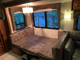 This RV rental interior shows a dinette converted into a comfortable bed, perfect for compact travel.. Keystone RV Cougar 2014
