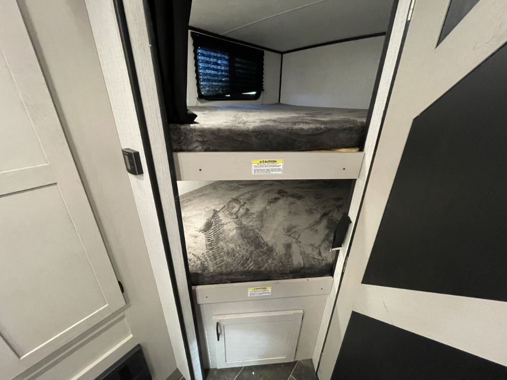 An RV rental's bunk bed sleeping area, featuring two cozy bunks with grey mattresses. Ideal for family travel.. Heartland RVs Mallard 2022
